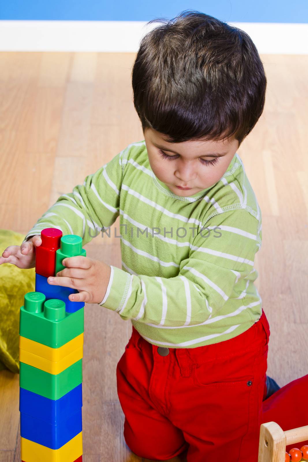 Baby is playing with educational toys over wooden background