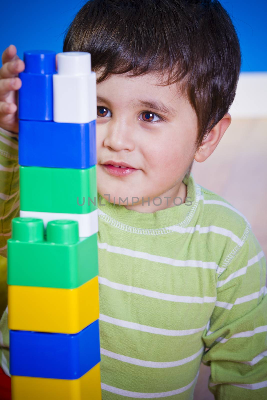 European boy playing with plastic colorful blocks by FernandoCortes