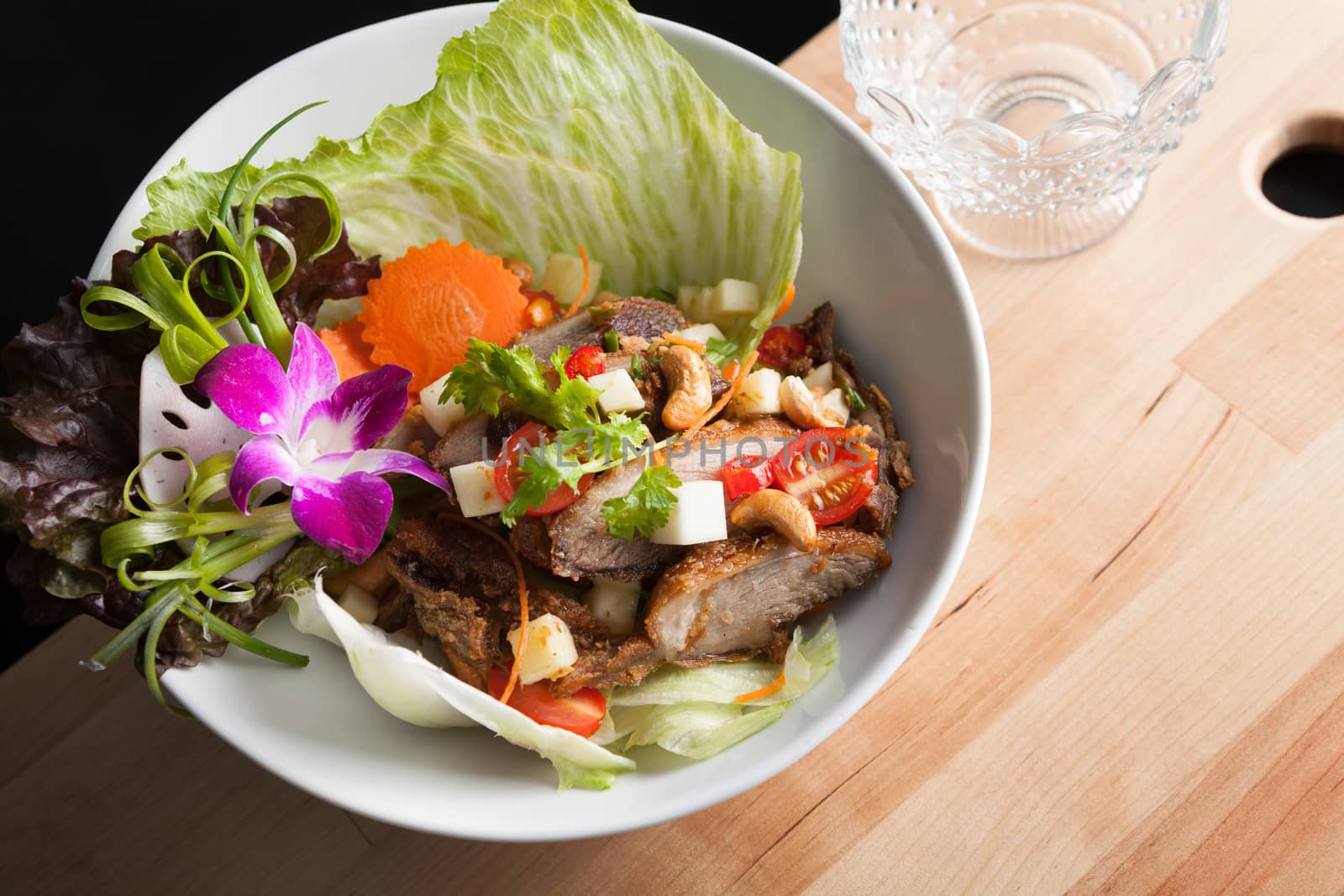 Thai Salad with Crispy Duck and fresh green mango tomatoes and cashew nuts on a bed of lettuce.