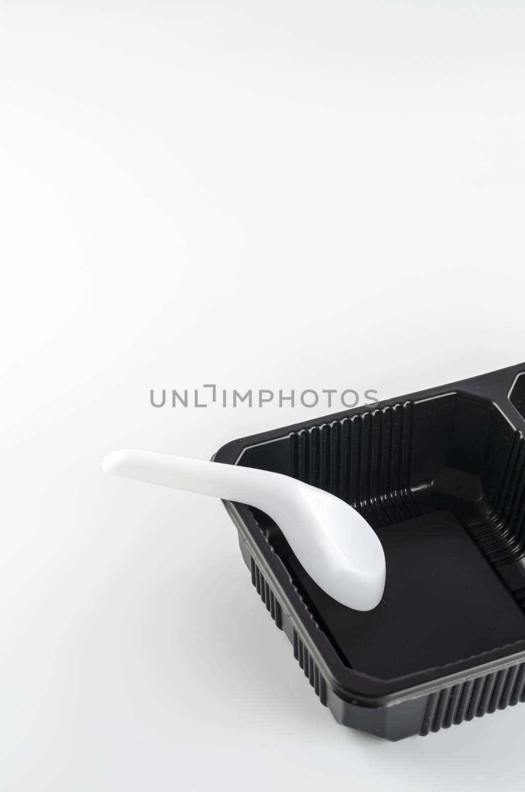 empty black plastic tray and spoon on a white background