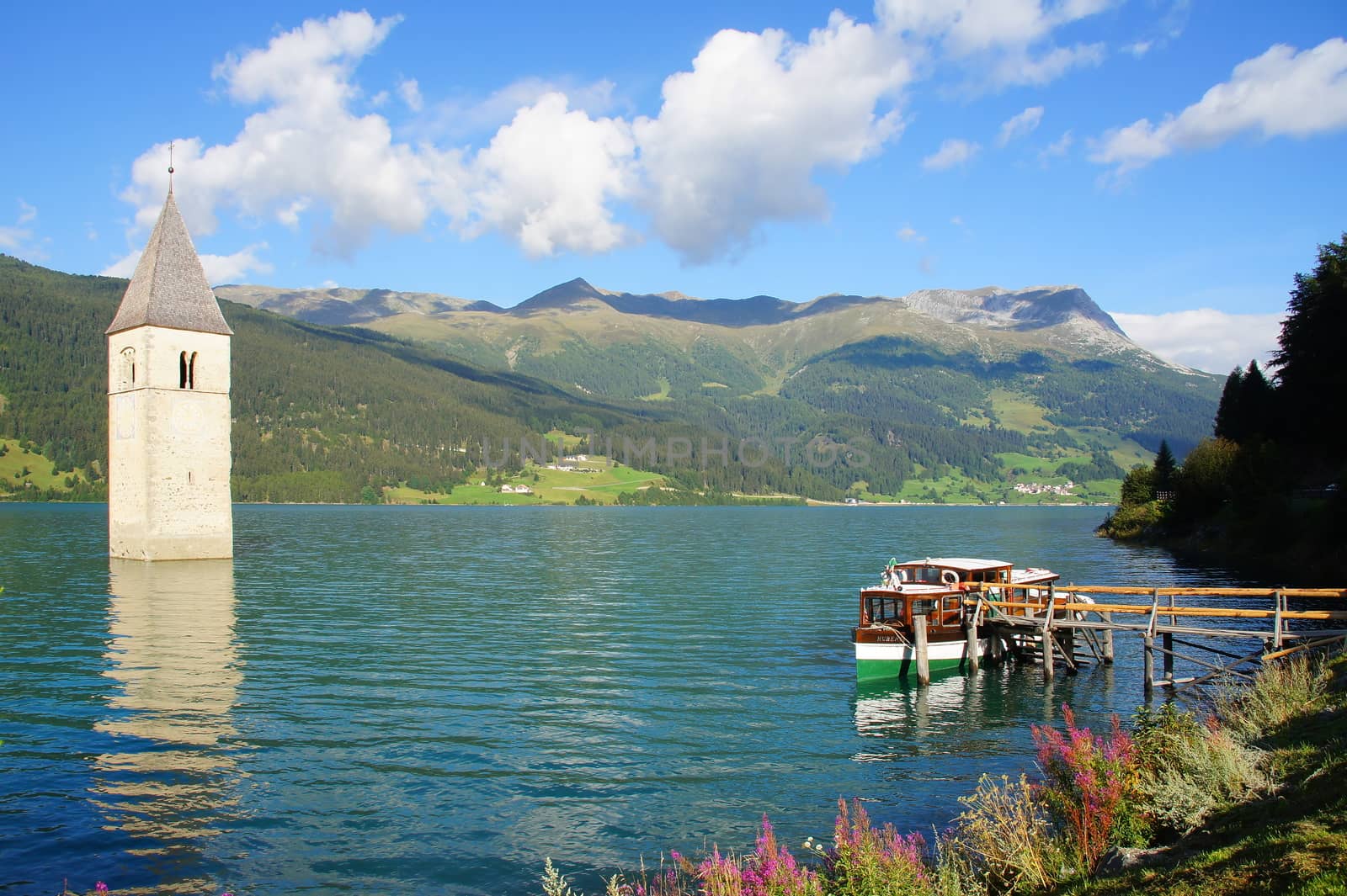 sunken church tower in lake Reschen with boat dock