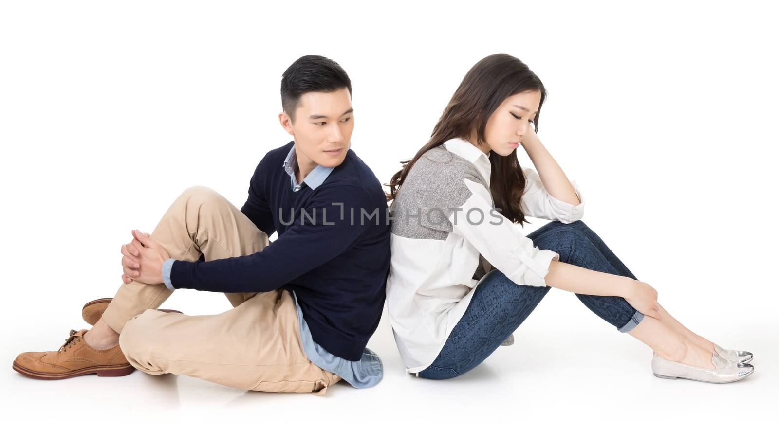 Young Asian couple sit on ground back to back and one turn back to care on studio white background.