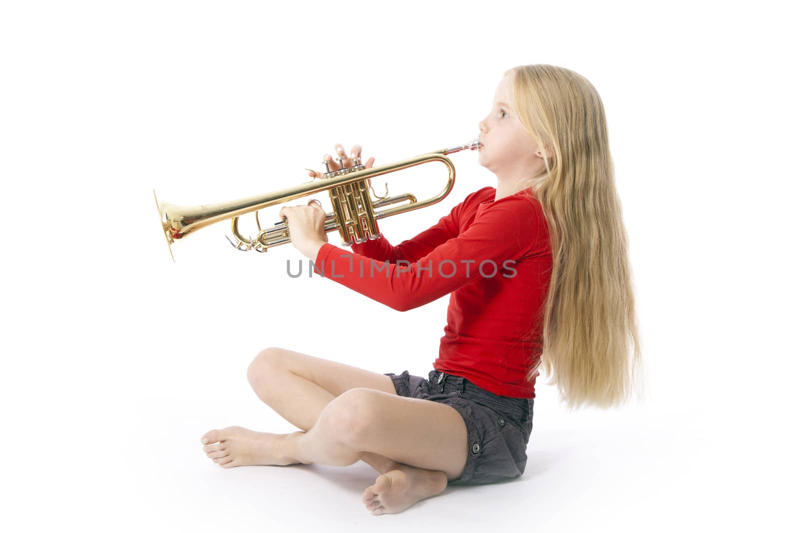young girl in red playing trumpet against white background