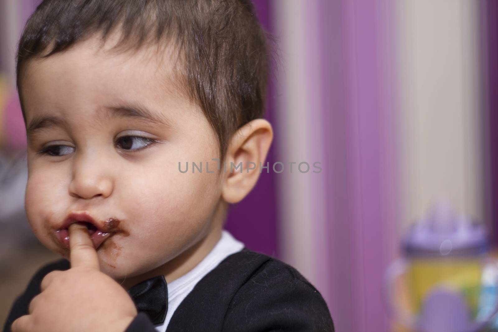 Adorable happy baby eating chocolate, wearing suit and bow tie by FernandoCortes