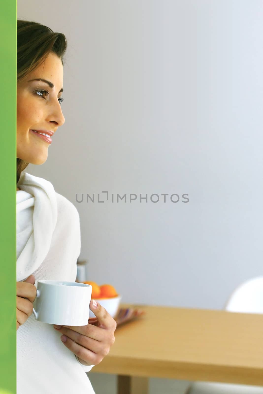 Relaxed beautiful woman drinking coffee in modern kitchen