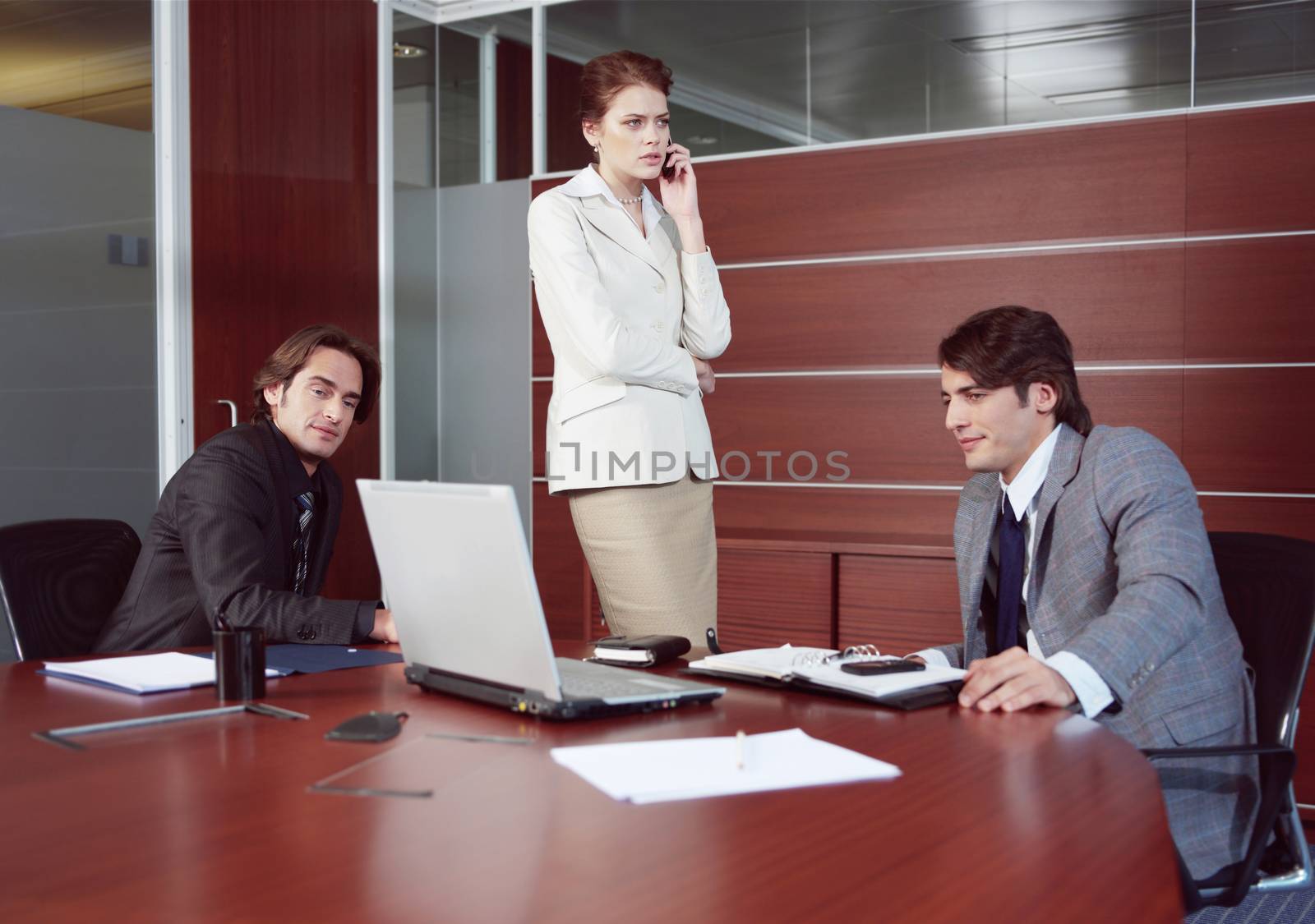 confident employees looking at monitor while their boss talking by phone 