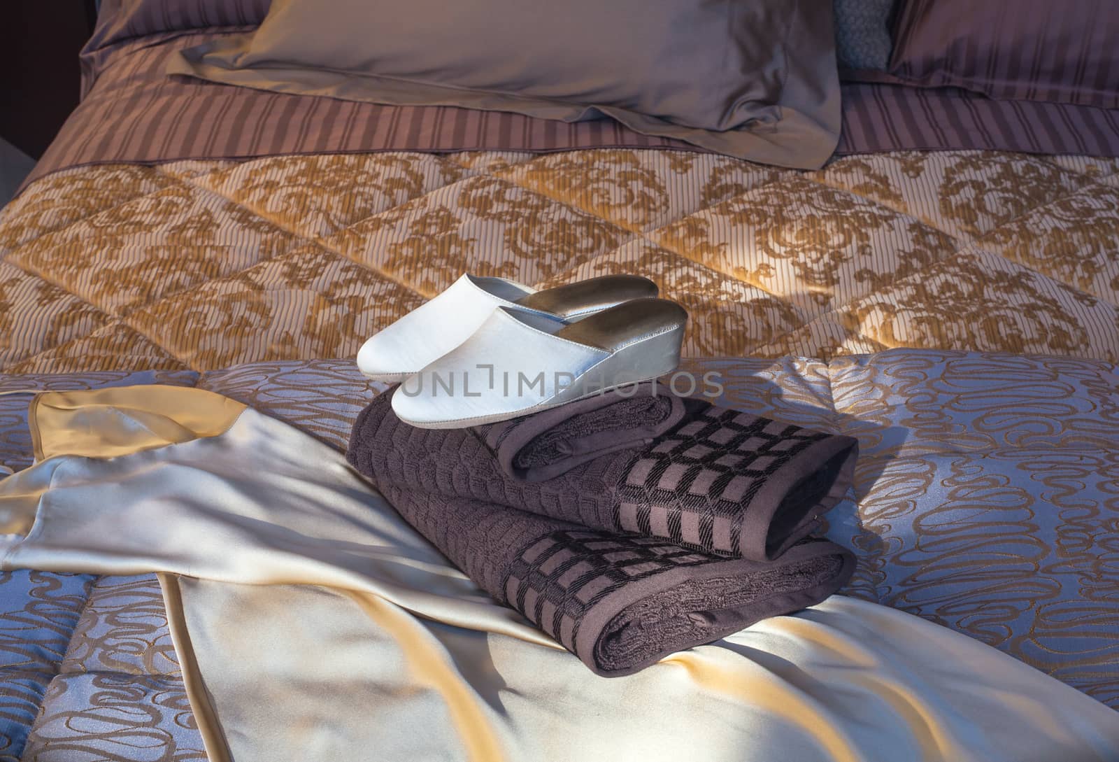 White female slippers on the towels in the bed