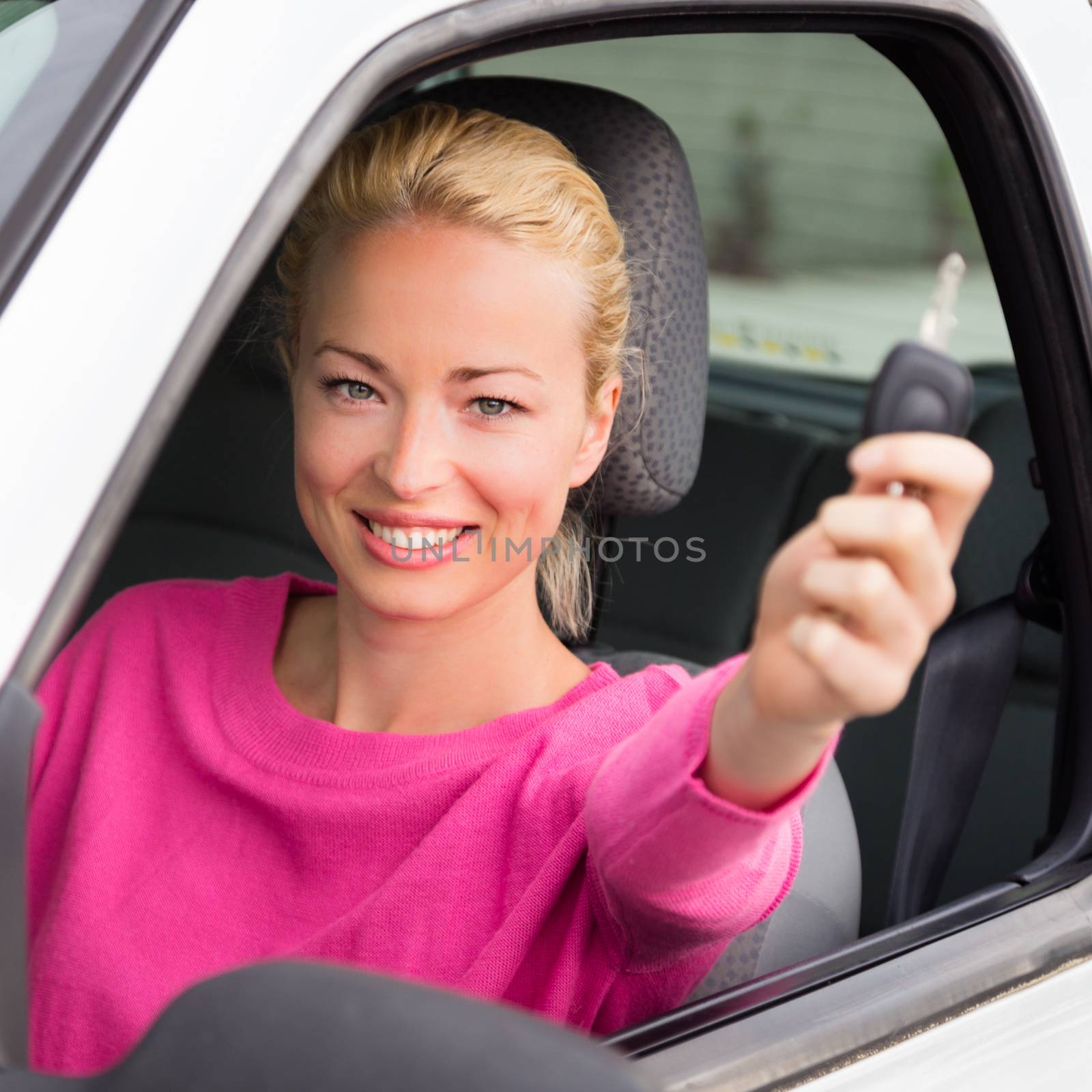 Woman driver showing car keys. Young female driving happy about her new car or drivers license. Caucasian model.