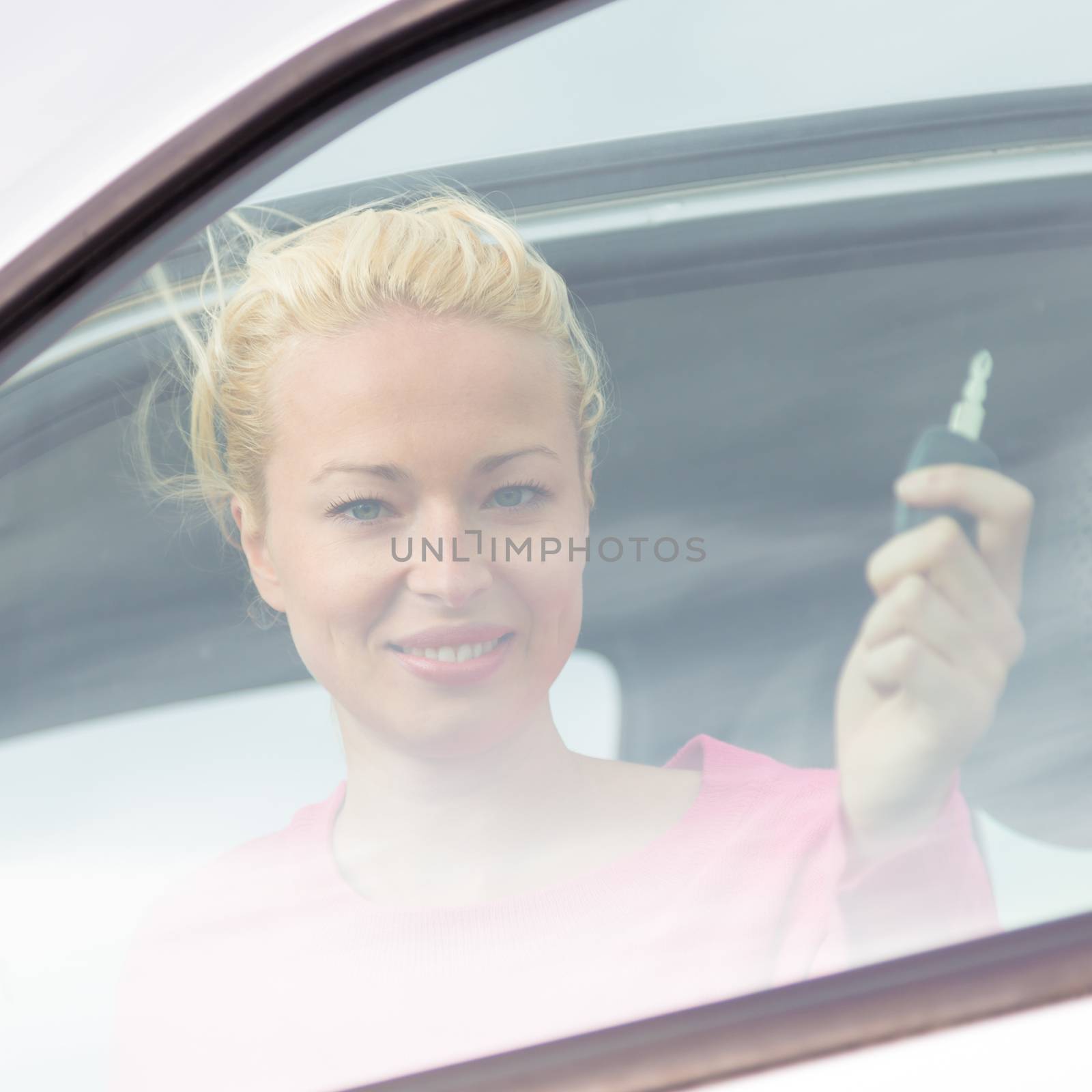 Woman driver showing car keys. Young female driving happy about her new car or drivers license. Caucasian model.