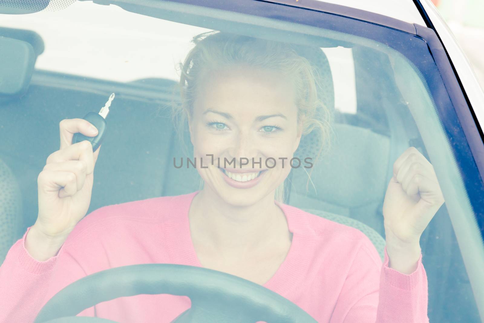 Woman driver showing car keys. Young female driving happy about her new car or drivers license. Caucasian model.