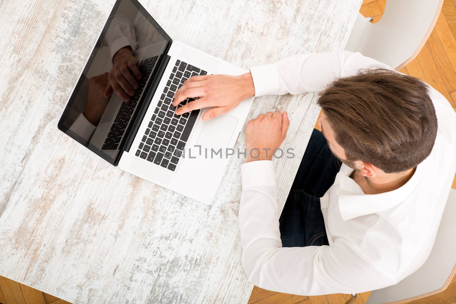 A young man sitting at the table with a laptop computer.