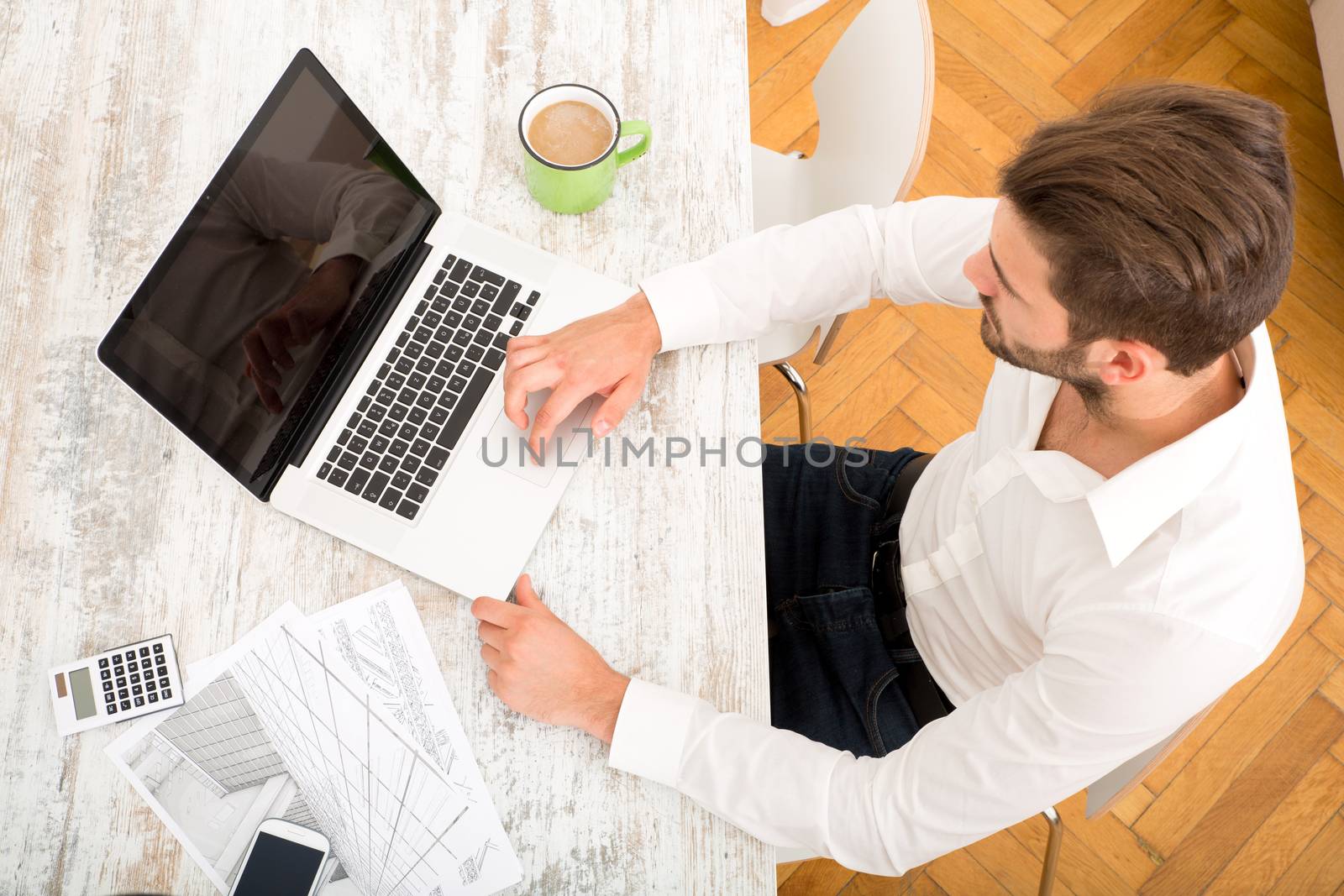 A young male architect working at home with a Laptop computer.