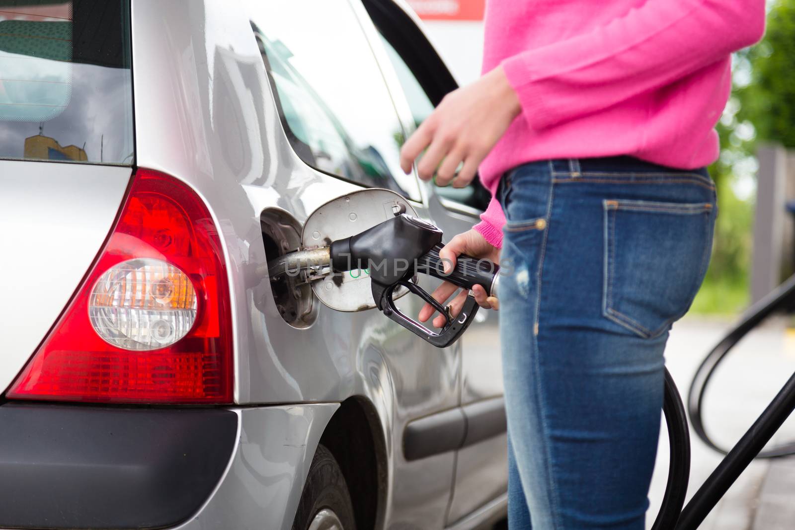 Lady pumping gasoline fuel in car at gas station. by kasto