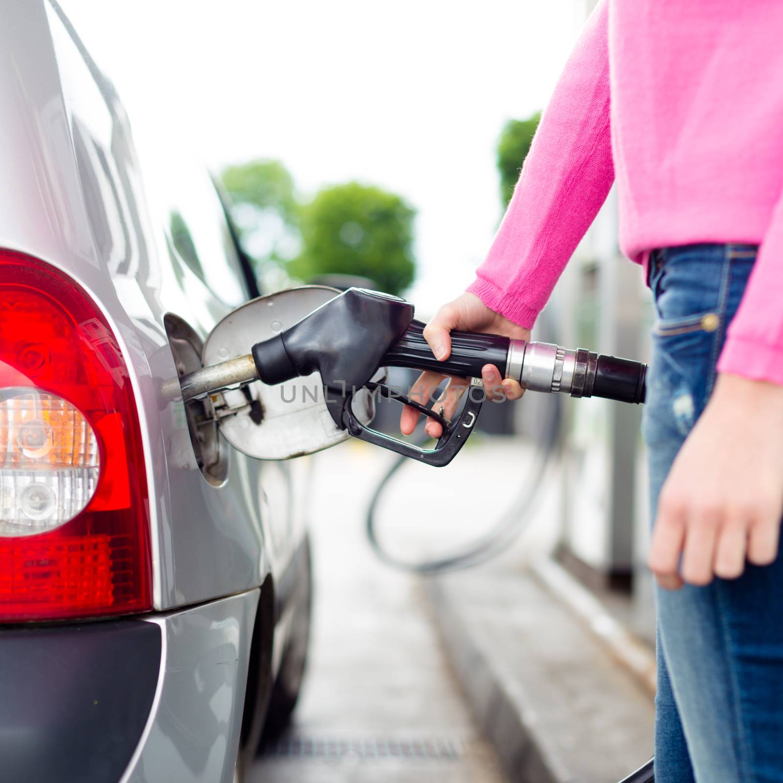 Closeup of woman pumping gasoline fuel in car at gas station. Petrol or gasoline being pumped into a motor vehicle car.