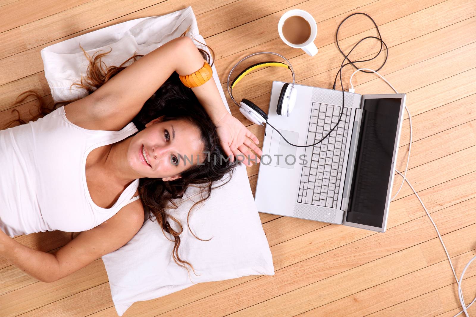 A girl laying on the Floor after surfing on the Internet with a Laptop.