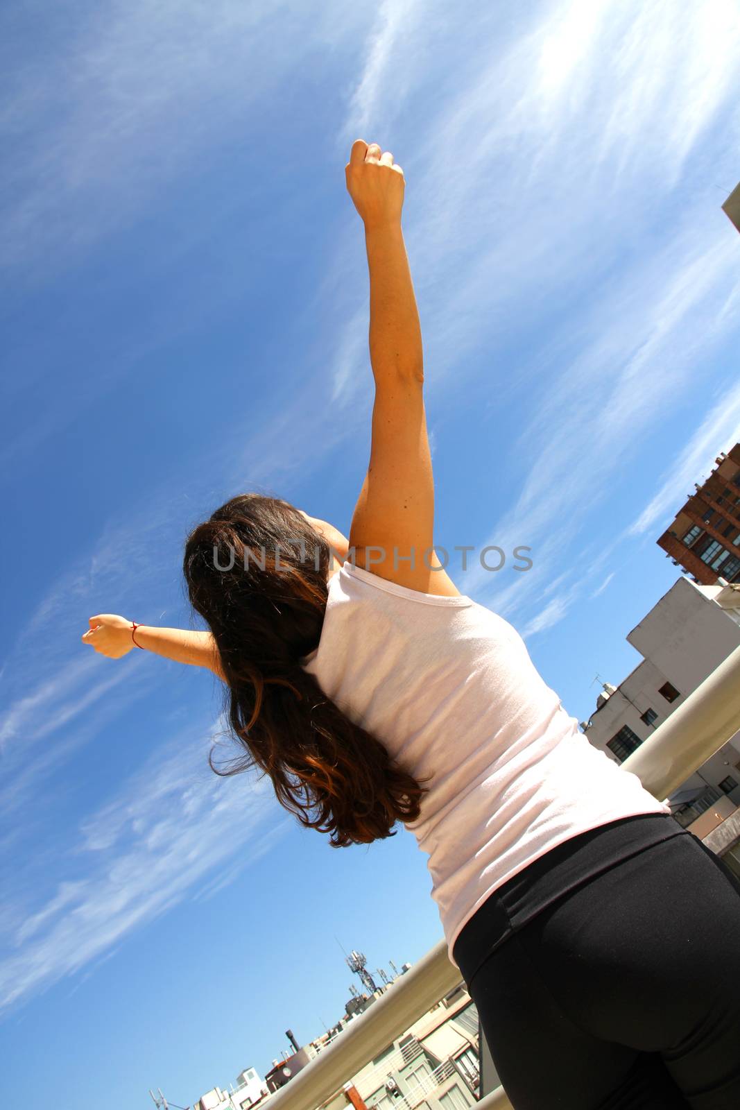 A young adult woman practicing Yoga in an urban environment.