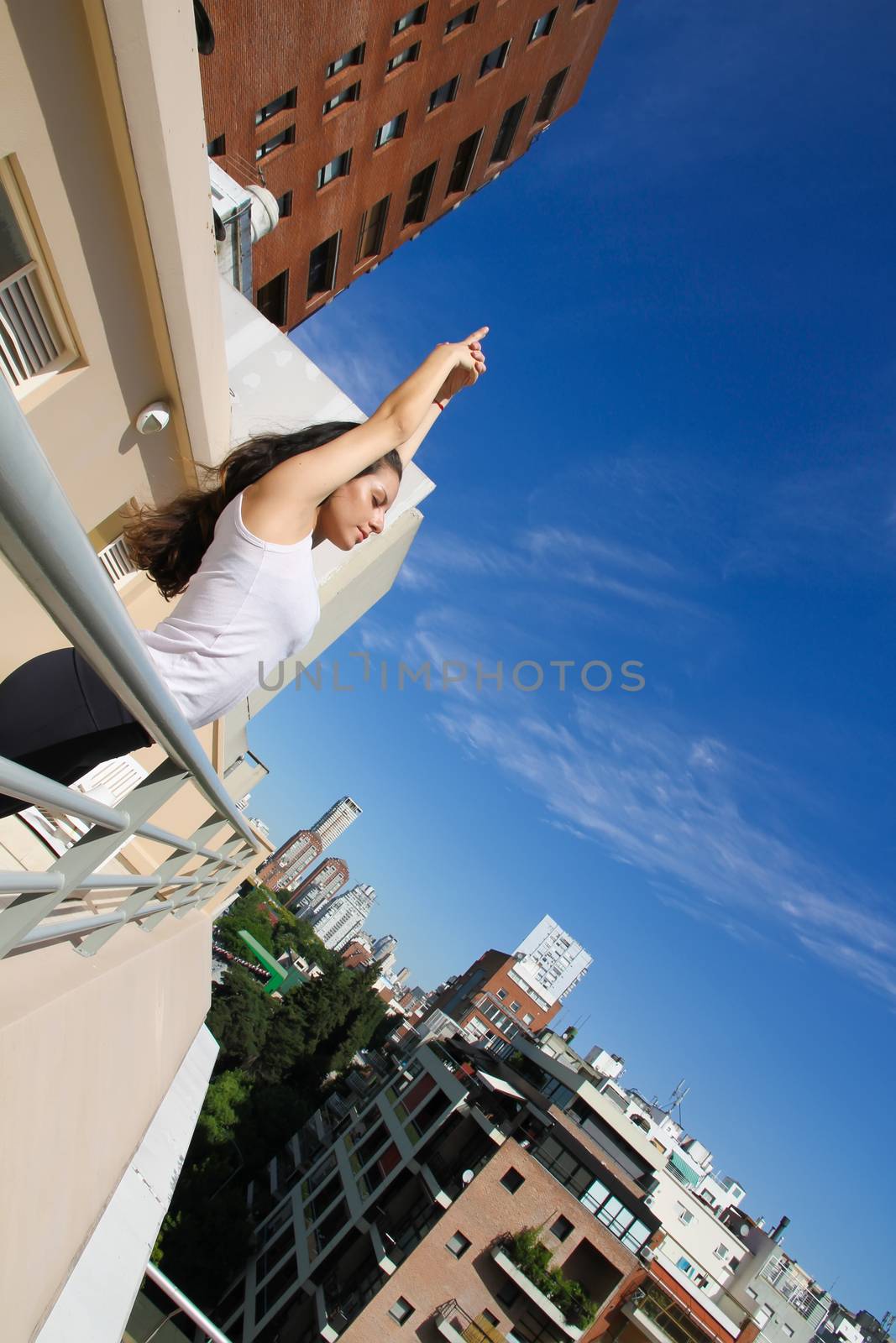 A young adult woman practicing Yoga in an urban environment.