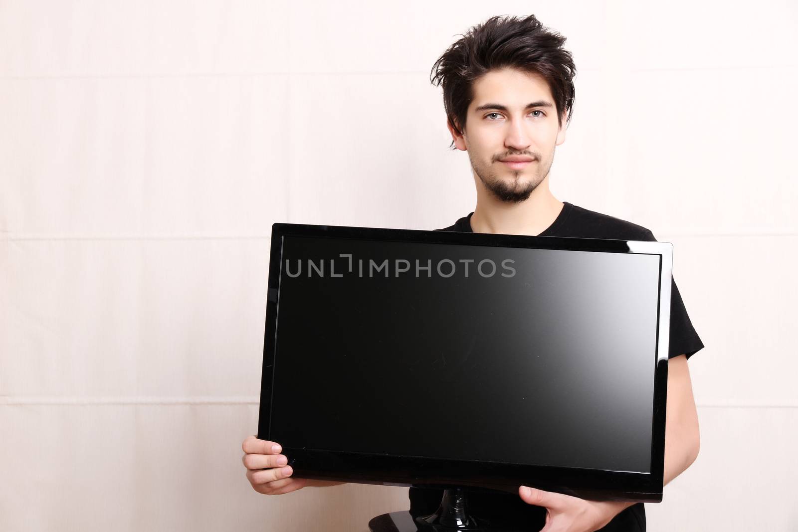 A young hispanic man holding a flatscreen TV.