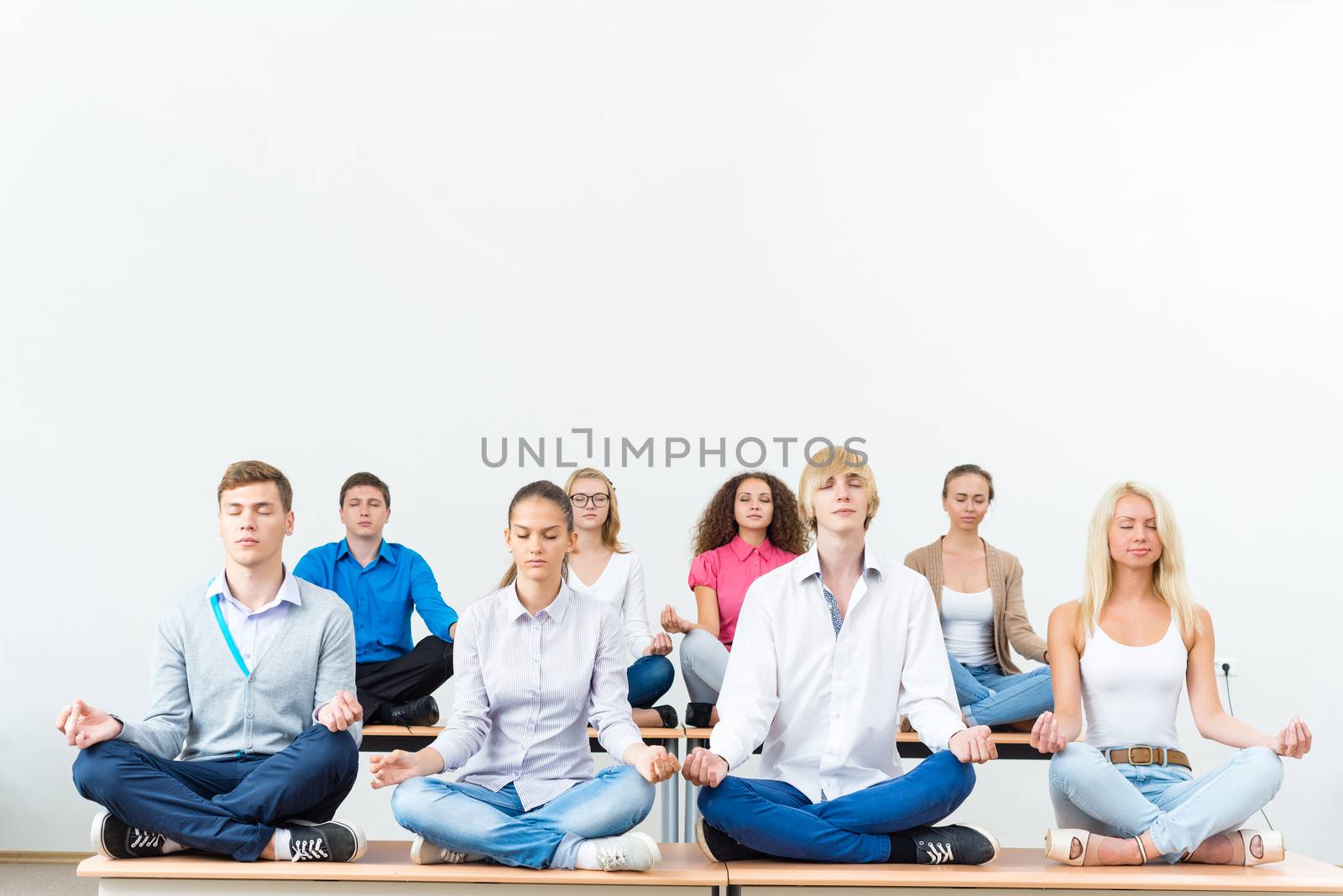 group of young people meditating in office at desk, group meditation