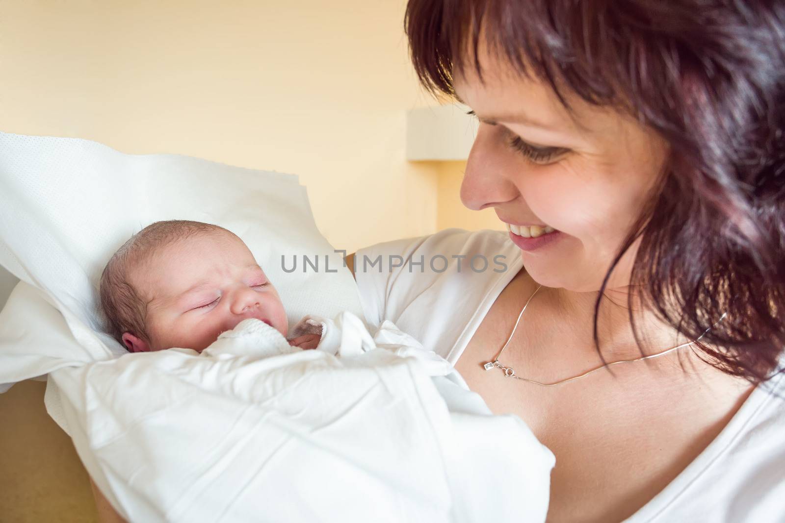 mother with her cute little baby girl in baby wrap, first hours of the new life, focus to infant