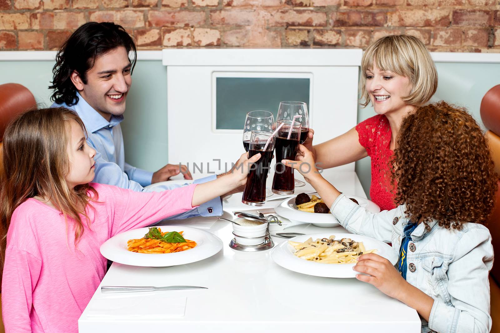 Happy family in a restaurant clinking their glasses