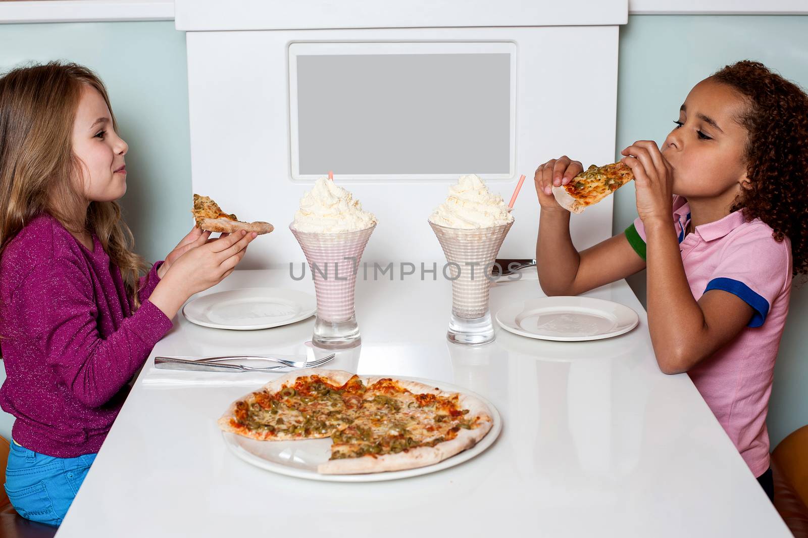 Cute girls eating pizza together in a restaurant
