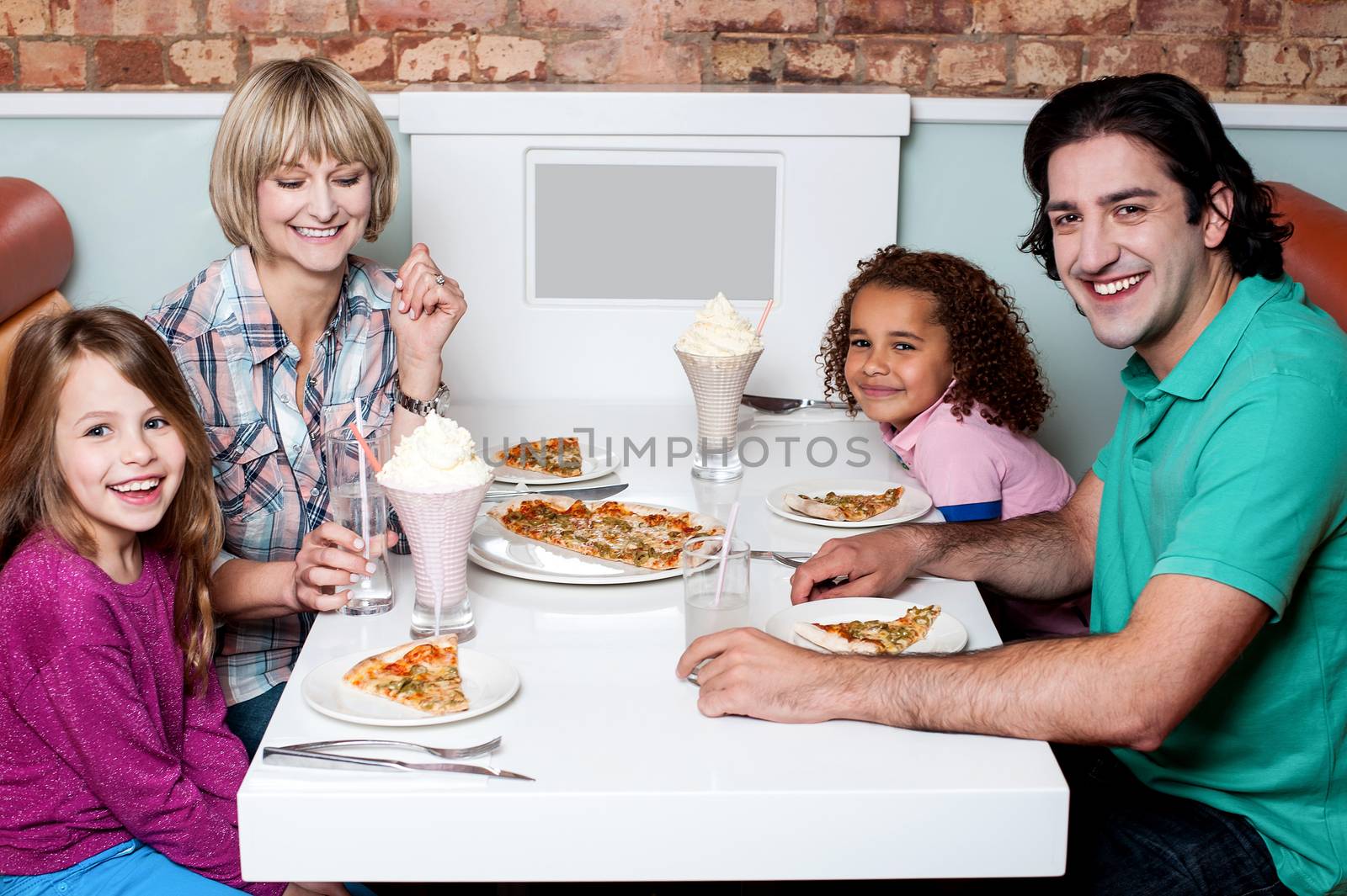 Family eating together in a restaurant by stockyimages