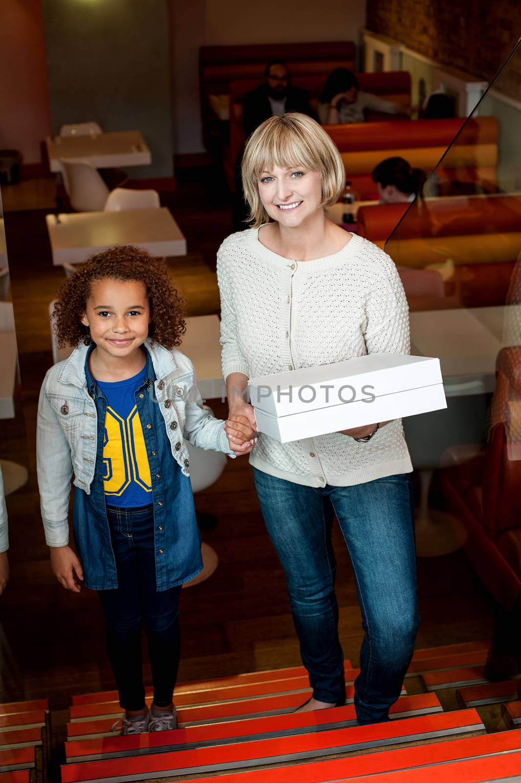 Mother holding daughter hand and pizza boxes