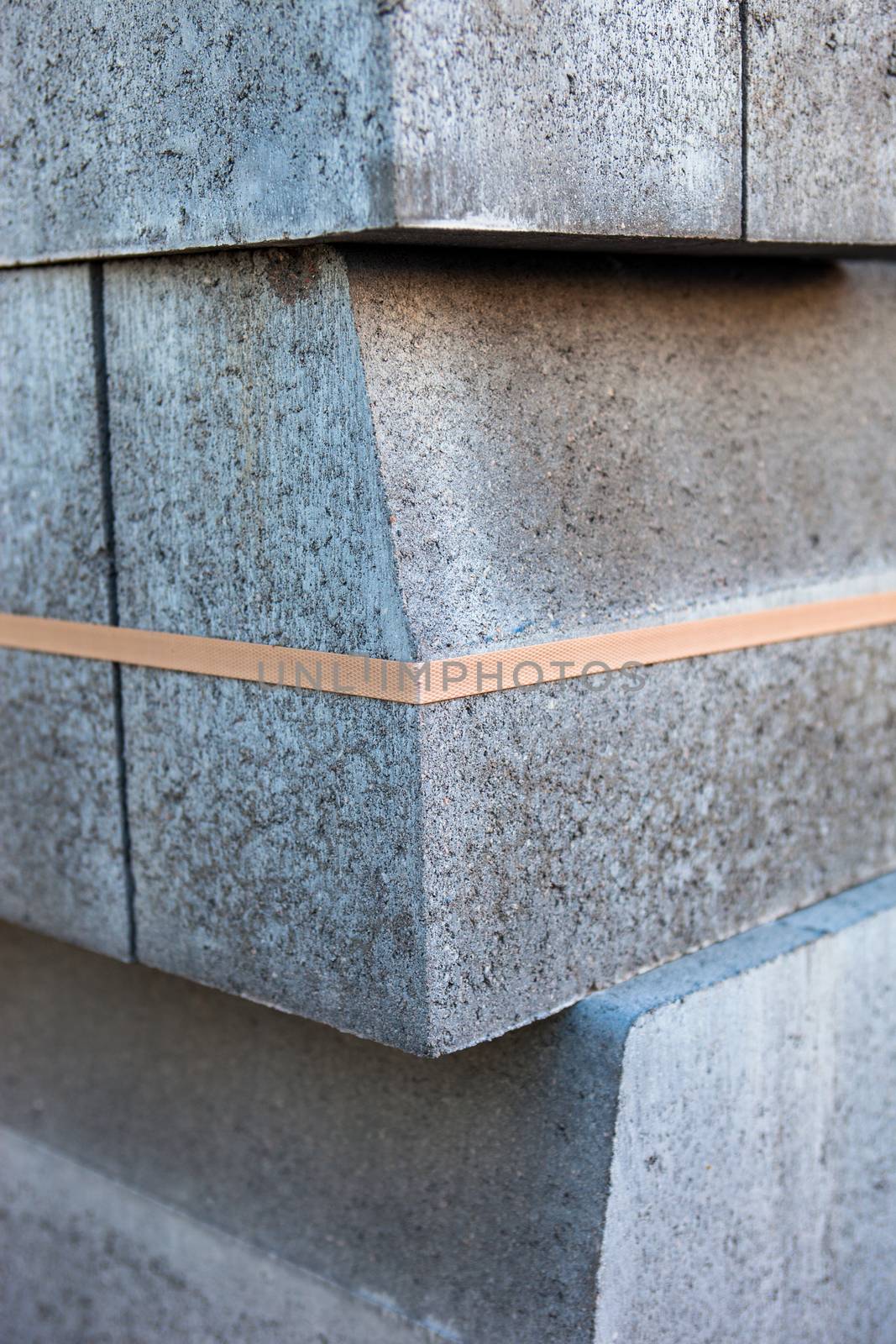 Stack of new concrete blocks tied-up with plastic stripe.