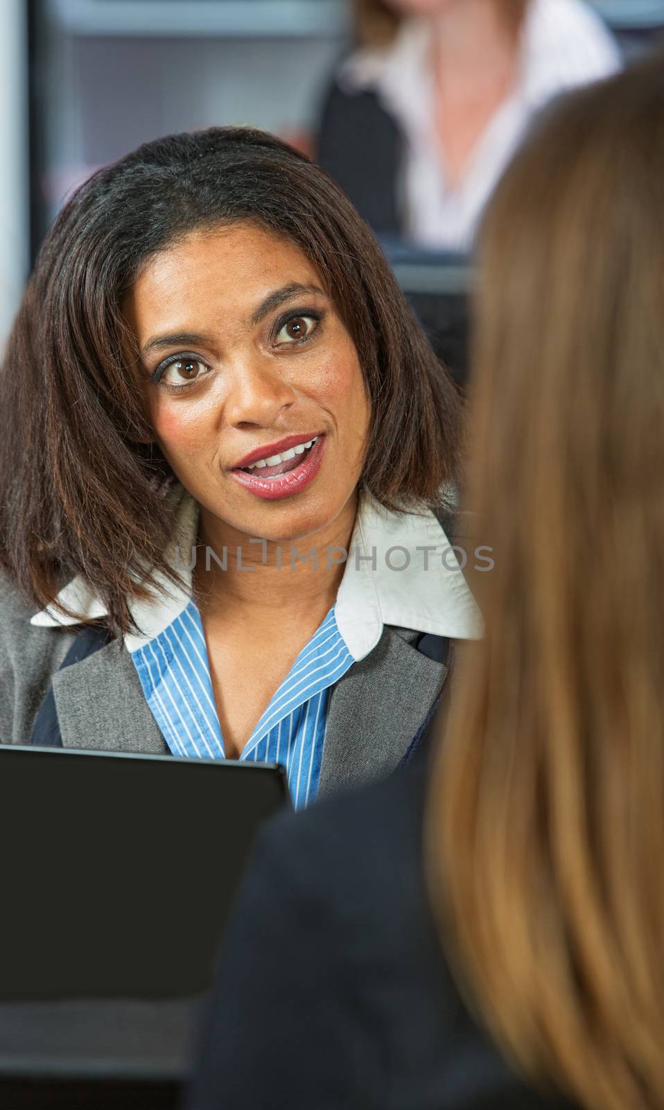 Amazed Black woman talking with friend in restaurant