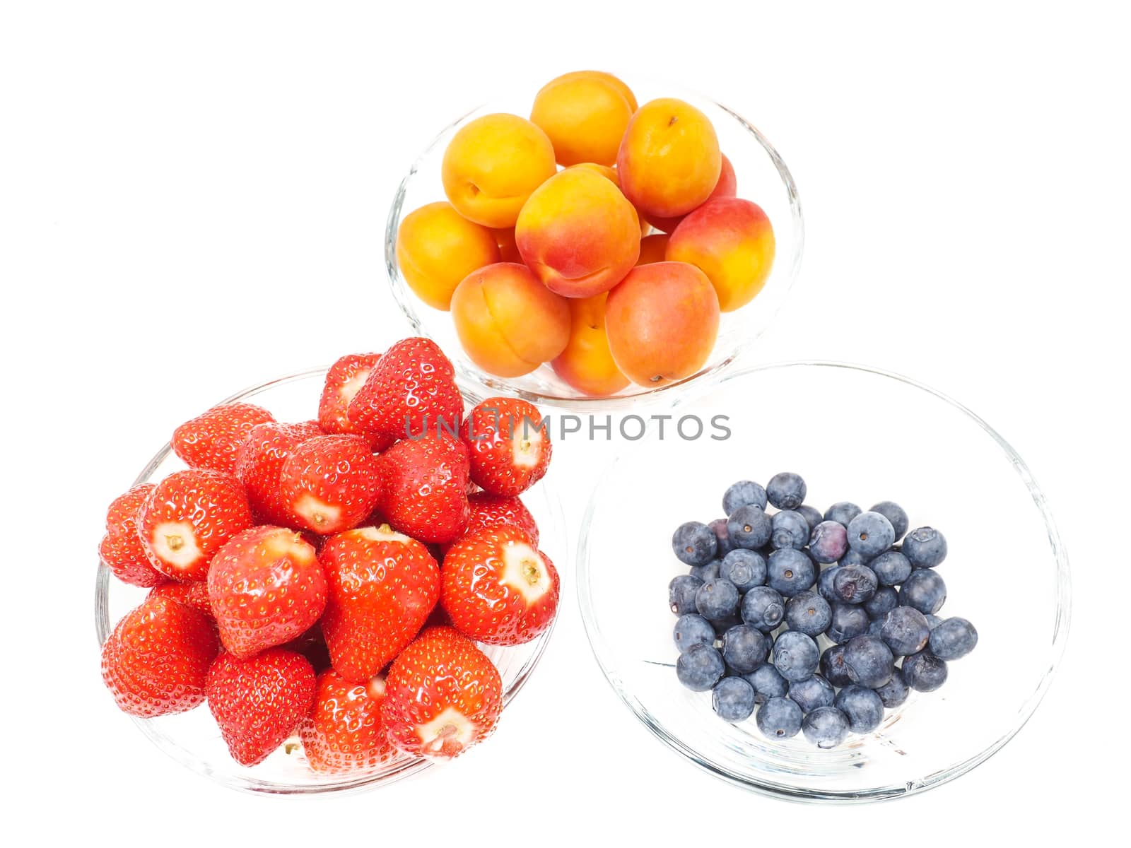 Strawberry, apricot and blueberries in glass bowls towards bright background