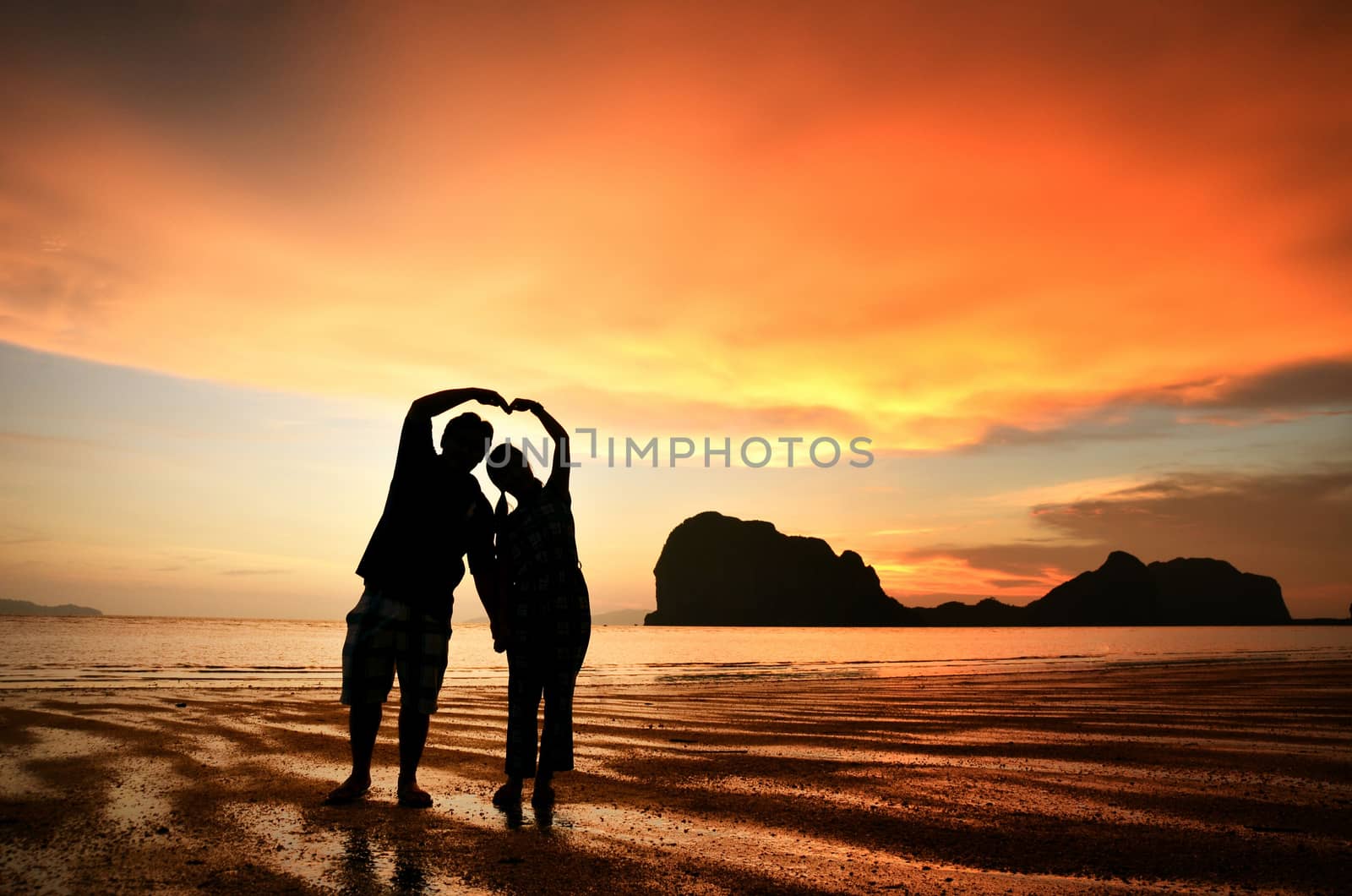 Romantic couple holding hands at sunset on the beach