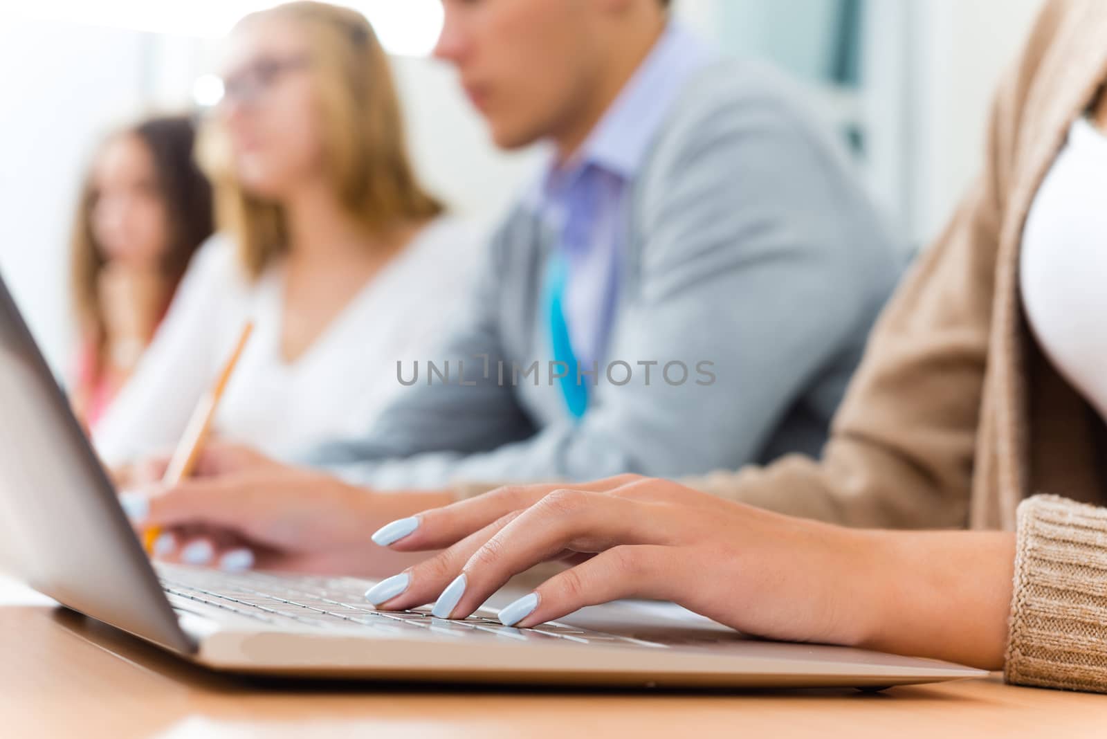 close-up of female hands on the laptop keyboard, students listen to the teacher at the University of