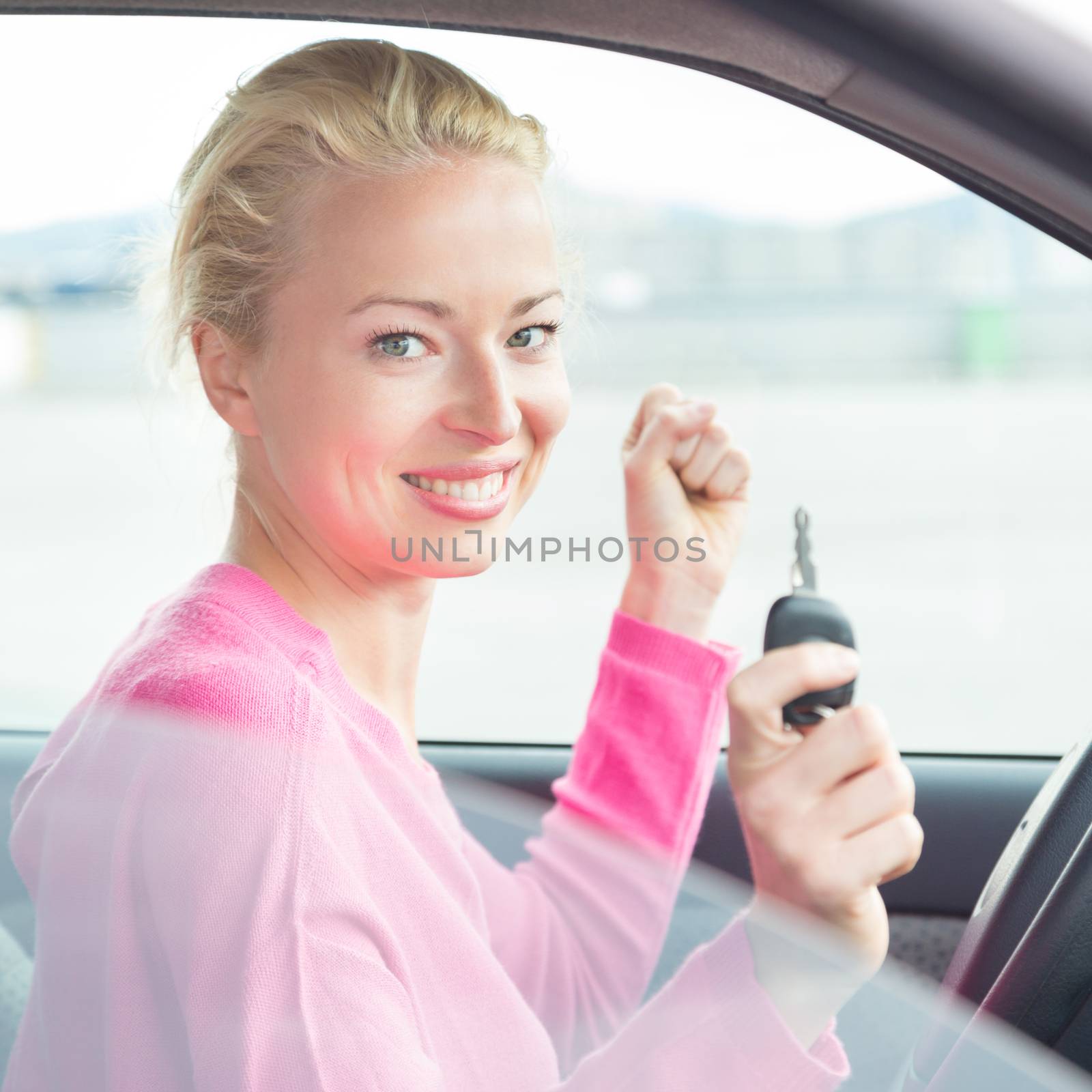 Woman driver showing car keys. Young female driving happy about her new car or drivers license. Caucasian model.