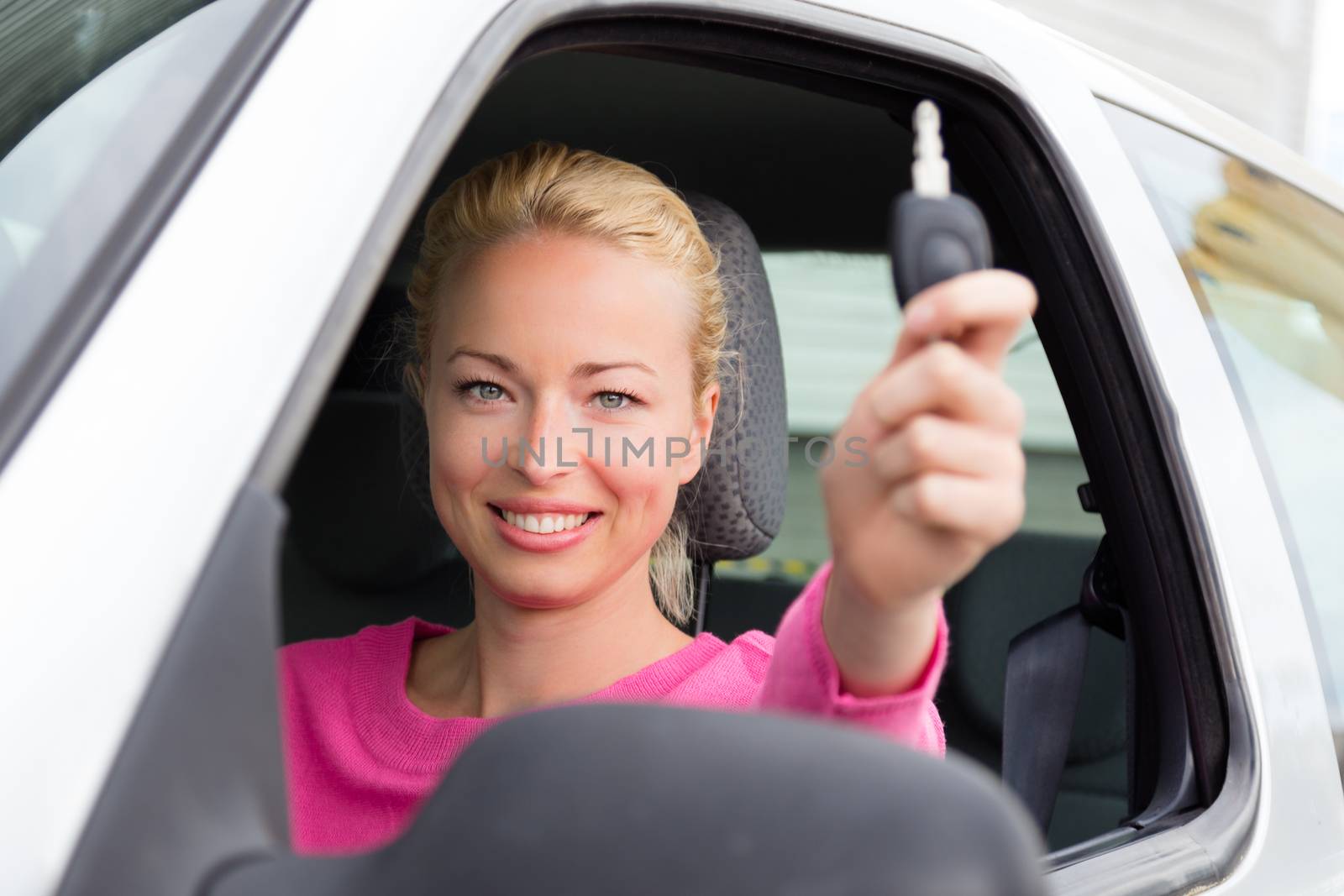 Woman driver showing car keys. Young female driving happy about her new car or drivers license. Caucasian model.