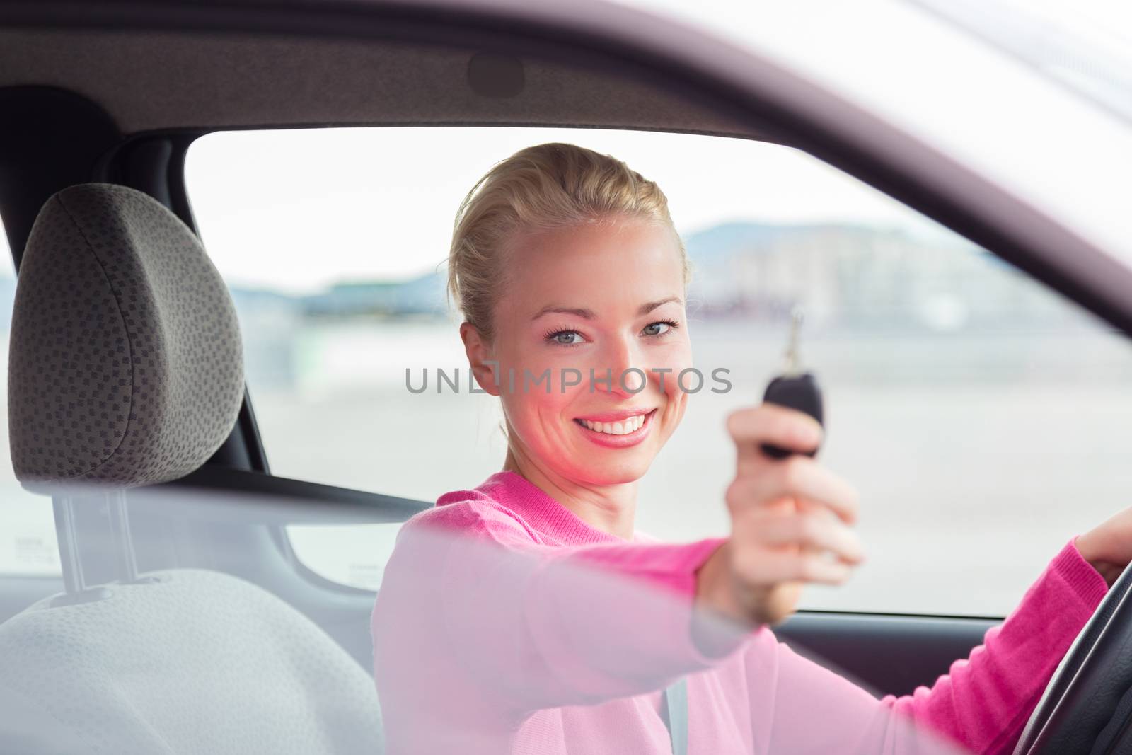 Woman driver showing car keys. Young female driving happy about her new car or drivers license. Caucasian model.