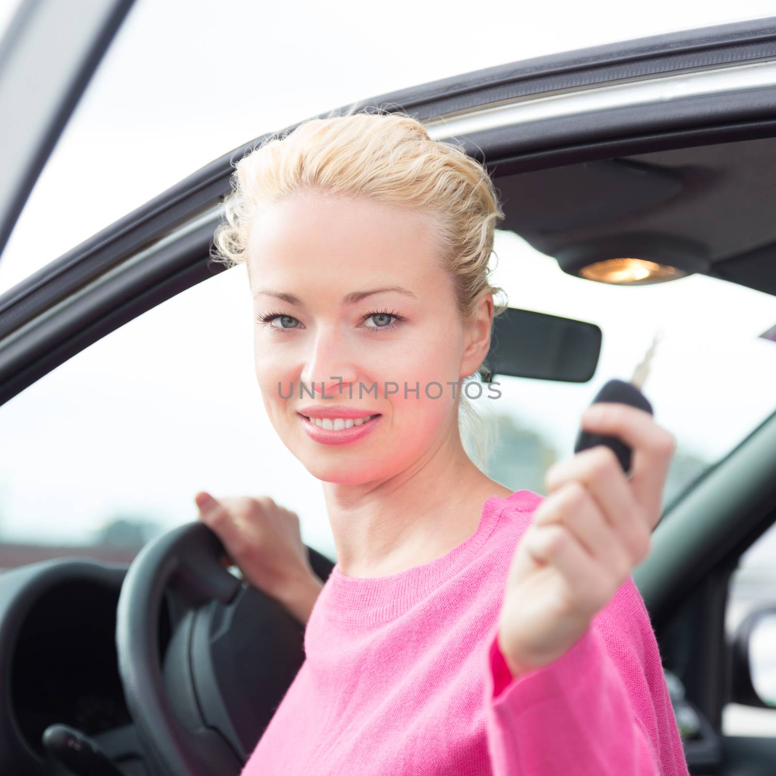 Woman driver showing car keys. Young female driving happy about her new car or drivers license. Caucasian model.