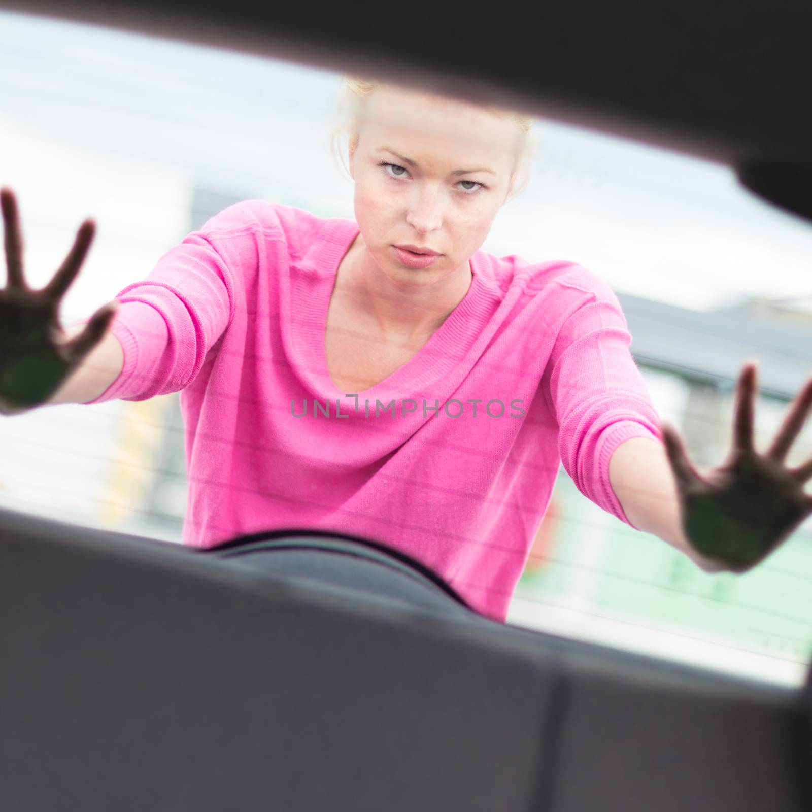 Self-sufficient, strong, young woman pushing a car. Engine breakdown.