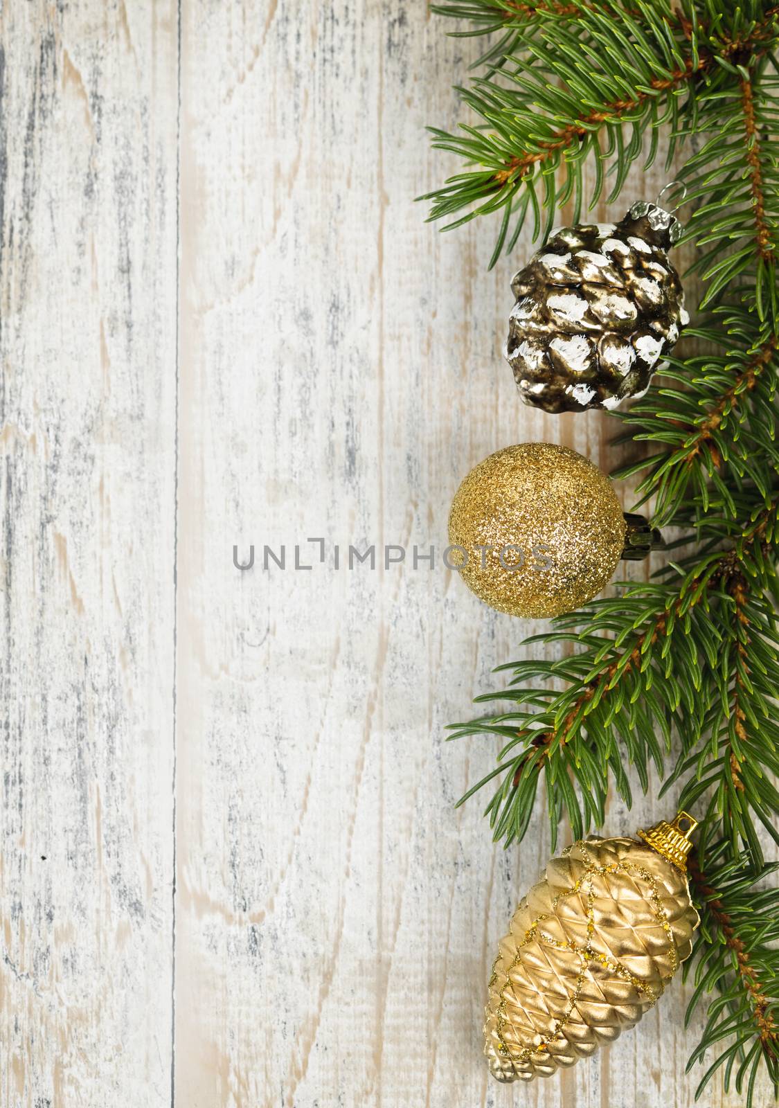 Christmas golden balls and pine cone on spruce branch with wooden background