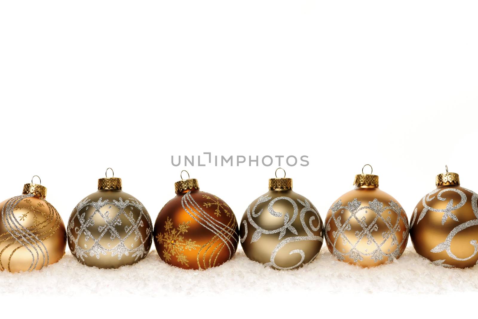 Row of golden Christmas balls with festive designs on snow