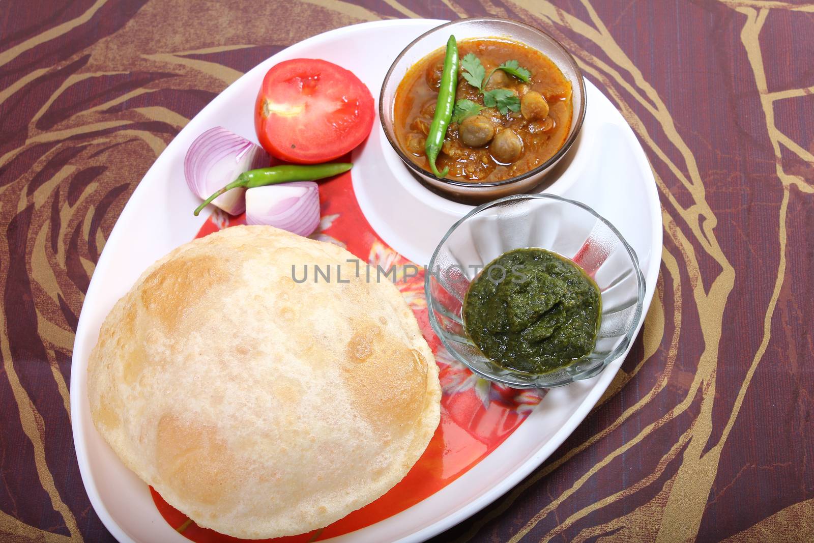 plate of spicy chole bhature, with green chili topping and chutney
indian dish
