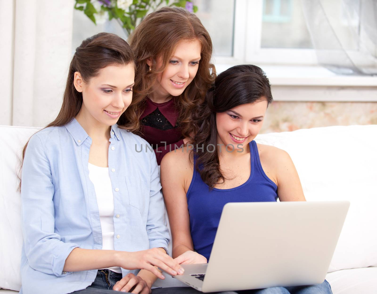 three young  smiling woman resting with notebook on sofa, at campus