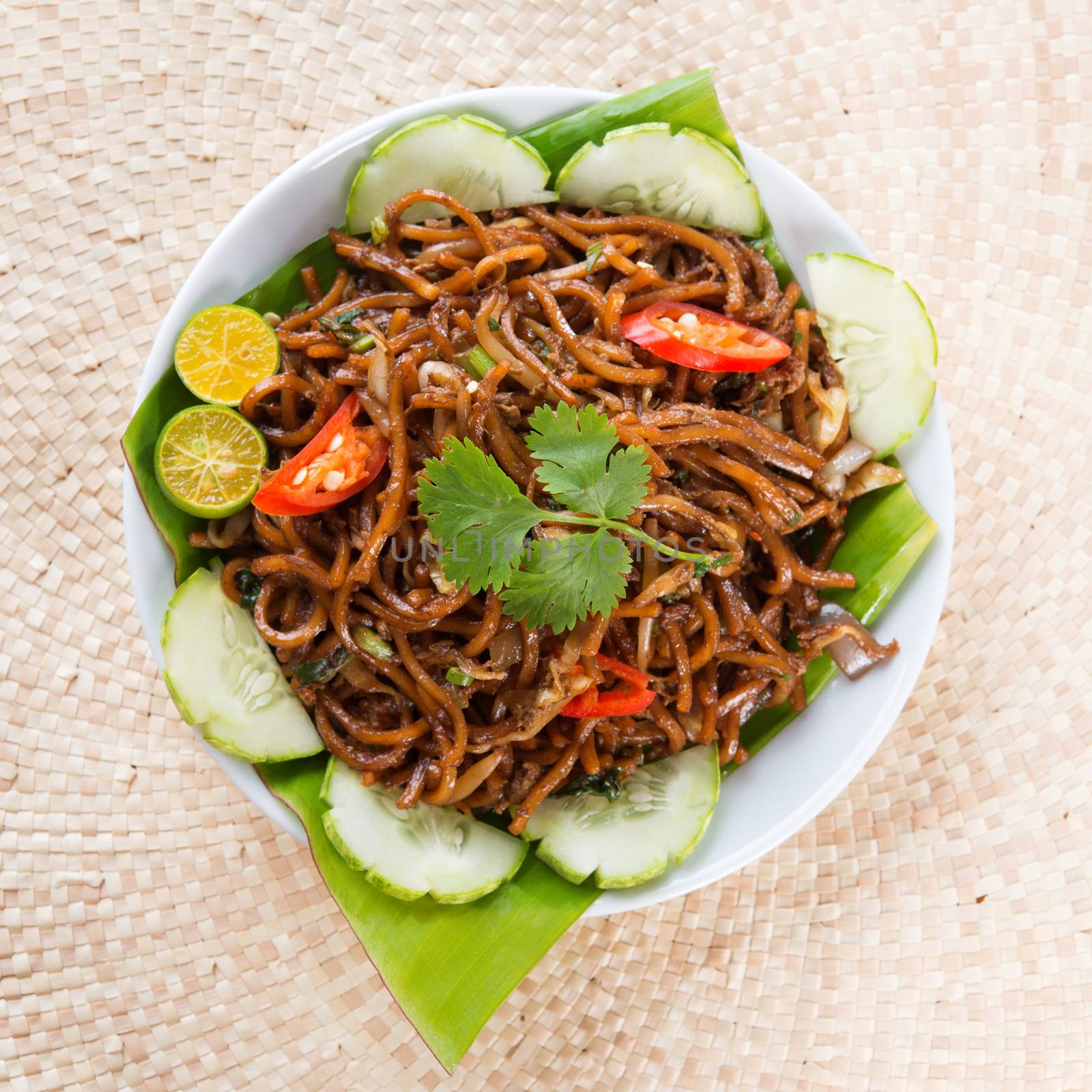 Asian food spicy fried noodles, ready to serve on dining table.