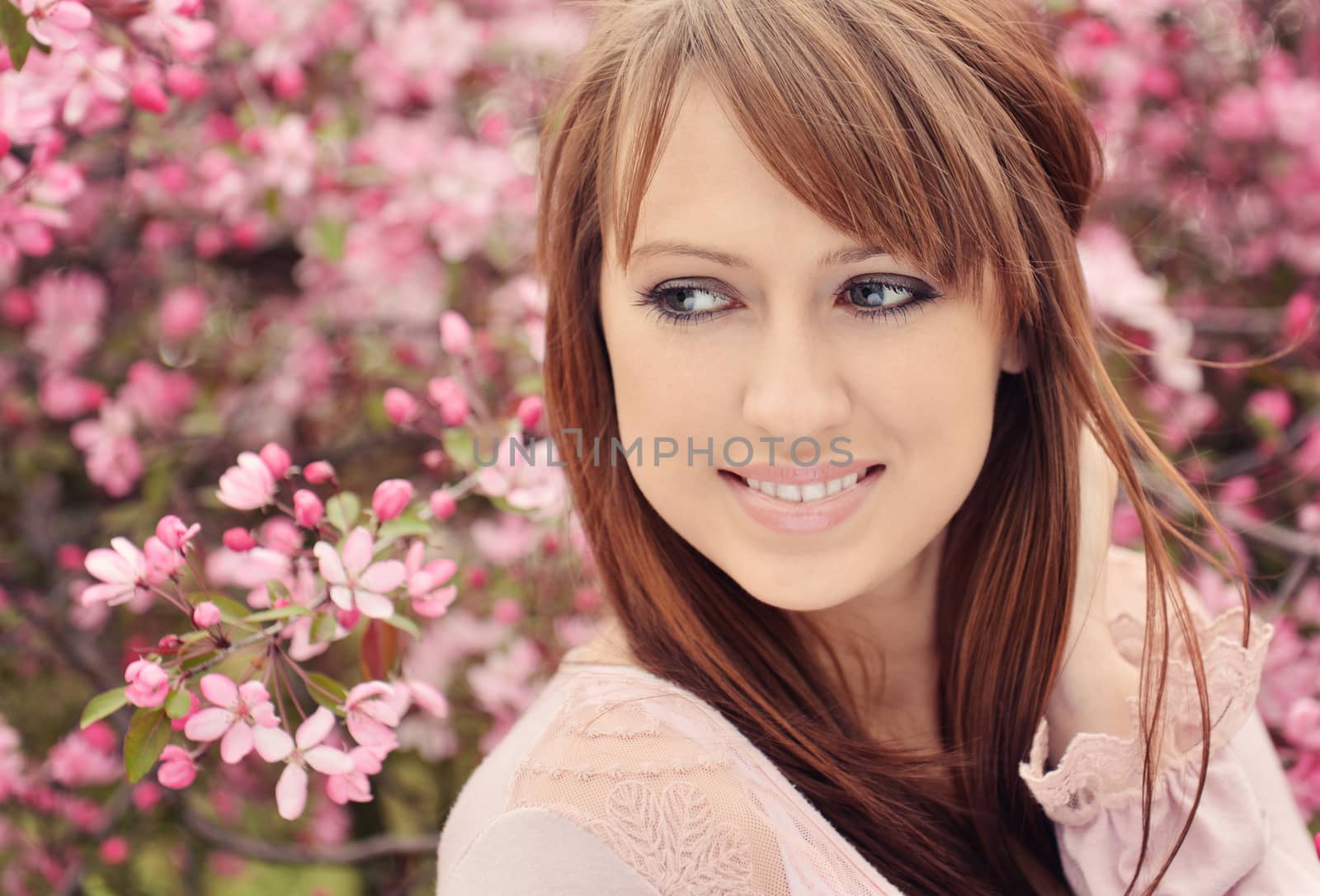 Beautiful girl posing over spring flowers background