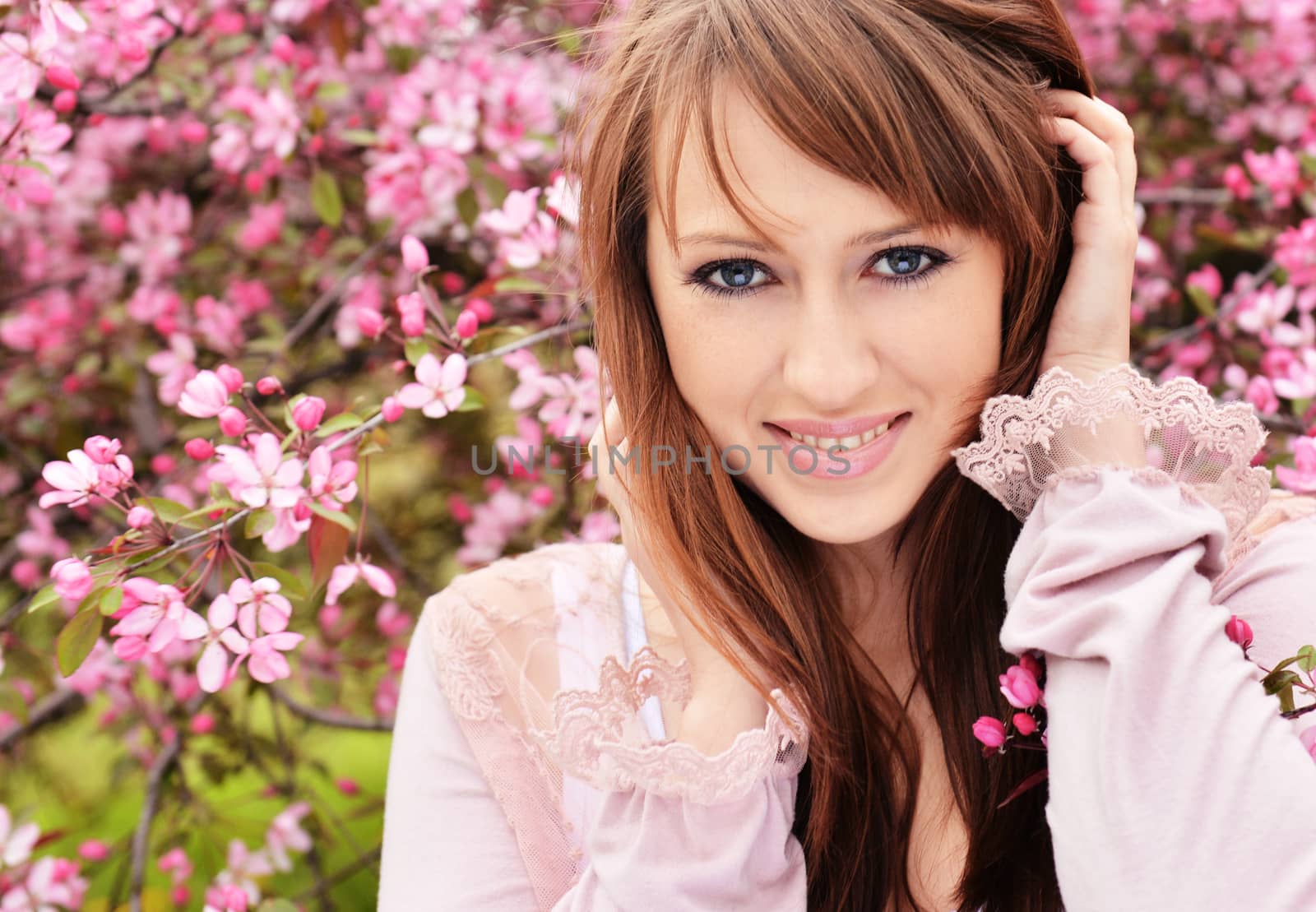 Beautiful girl posing over spring flowers background