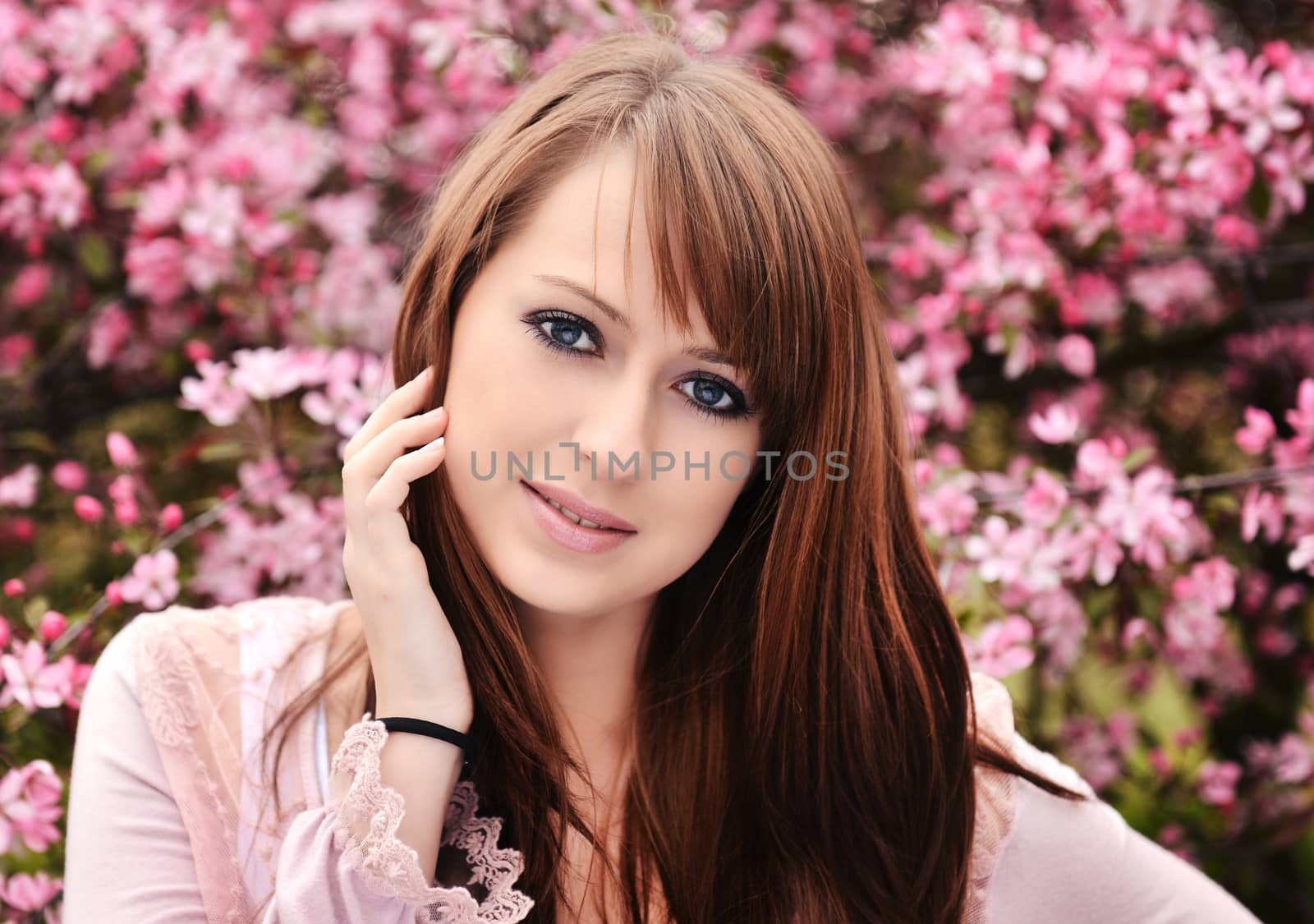 Beautiful girl posing over spring flowers background