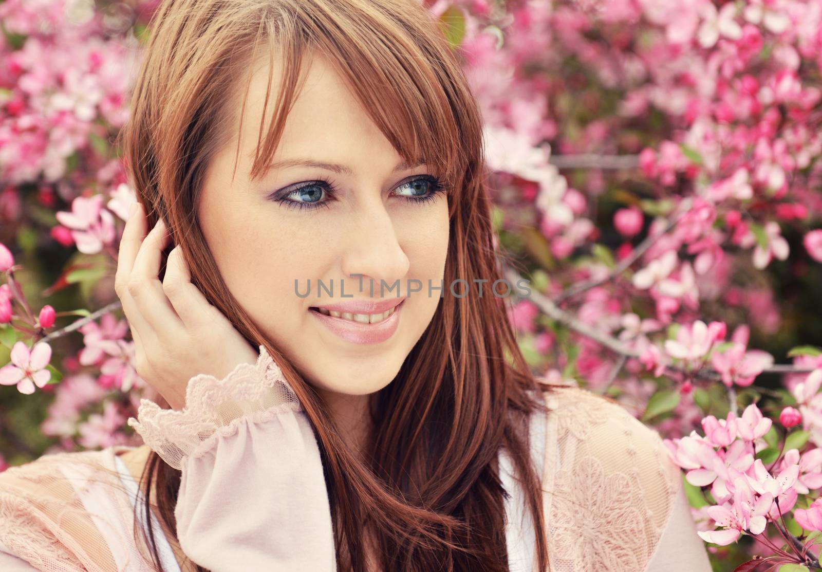 Beautiful girl posing over spring flowers background