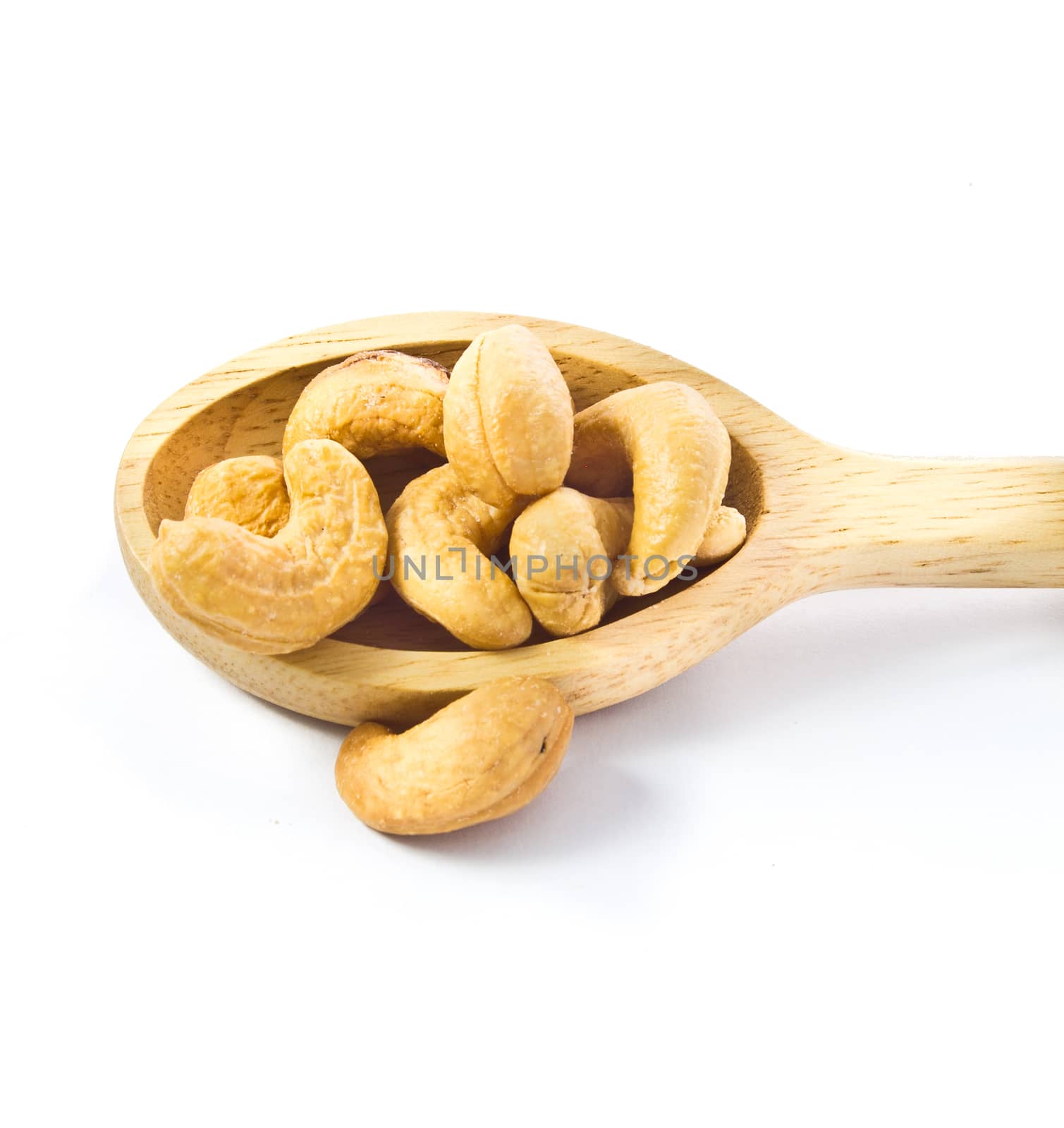 cashews nut in wood spoon isolated on white  background by tisskananat