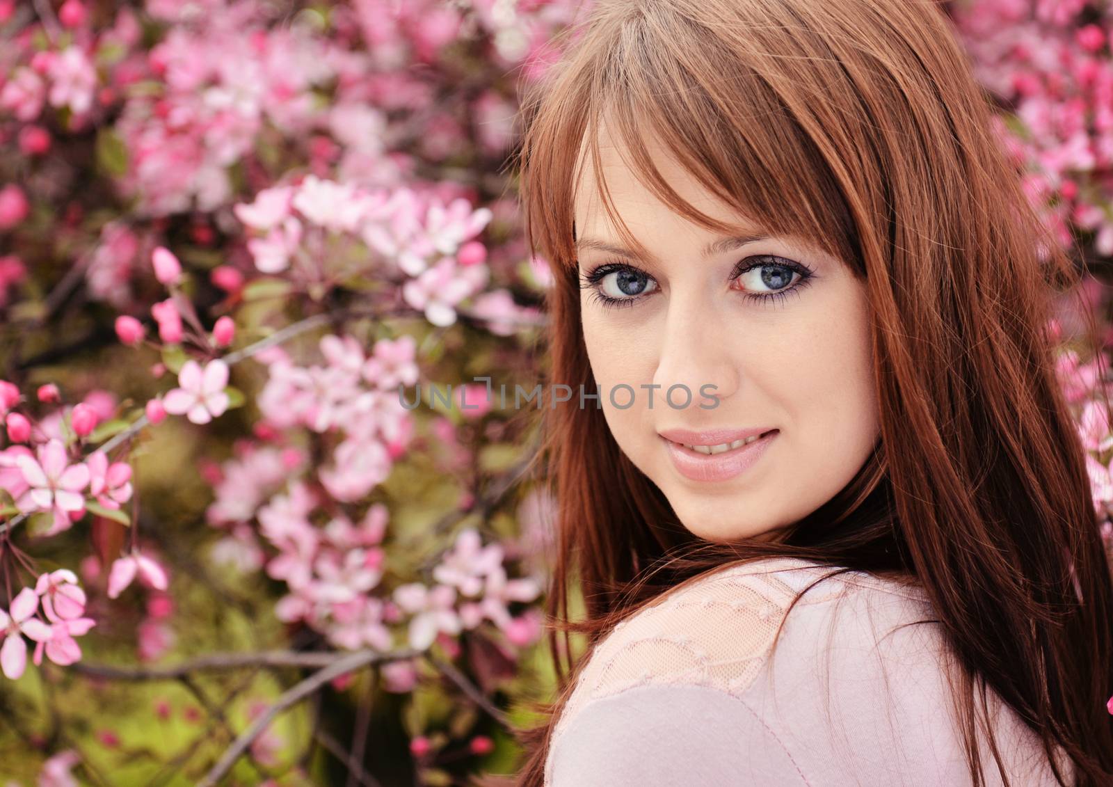 Beautiful girl posing over spring flowers background