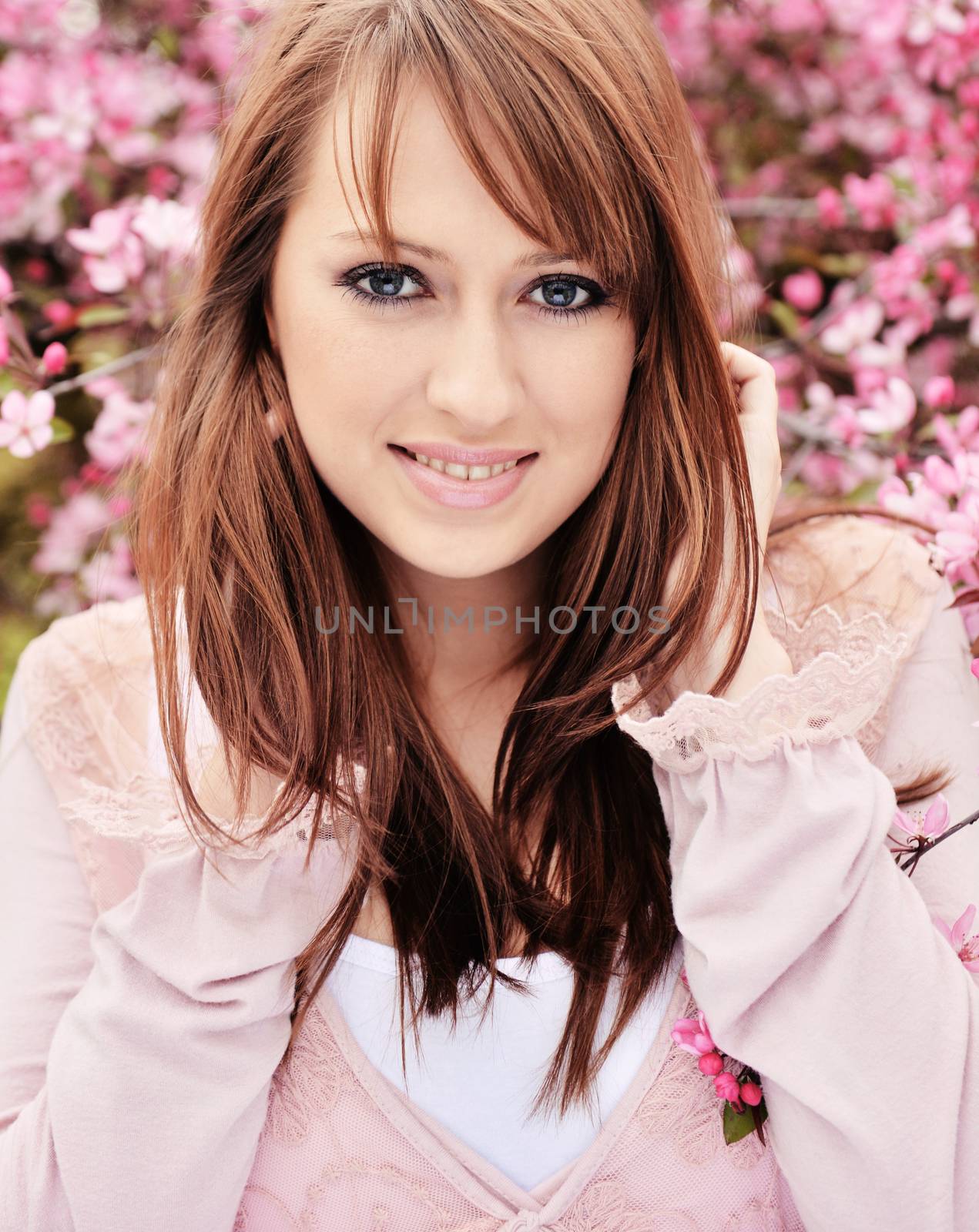 Beautiful girl posing over spring flowers background